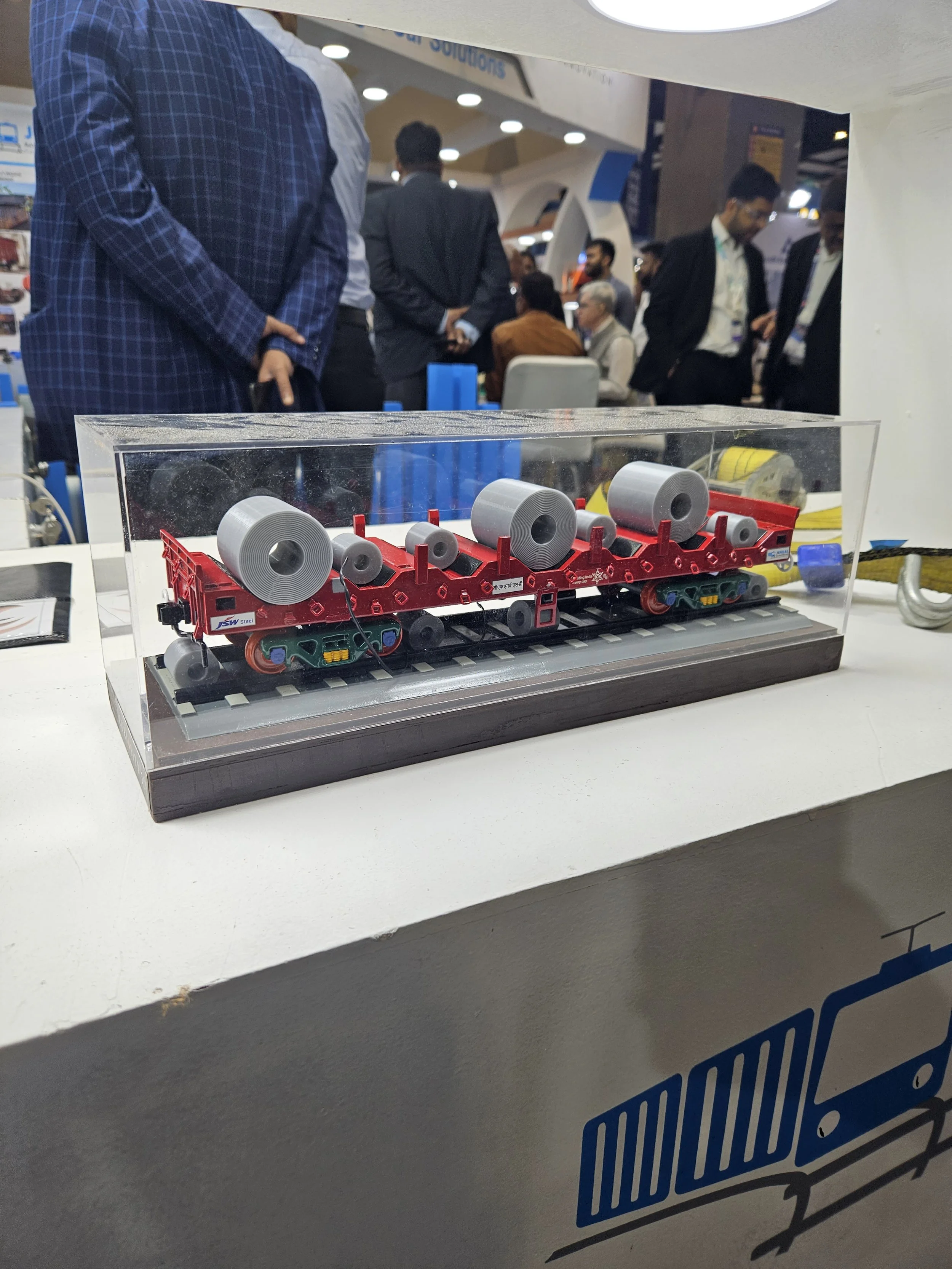 Miniature model of a train with large rolls, displayed in a case, at an exhibition setup.