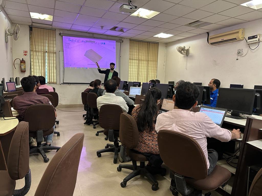 Classroom with computers and a projector, showing a teacher instructing students.