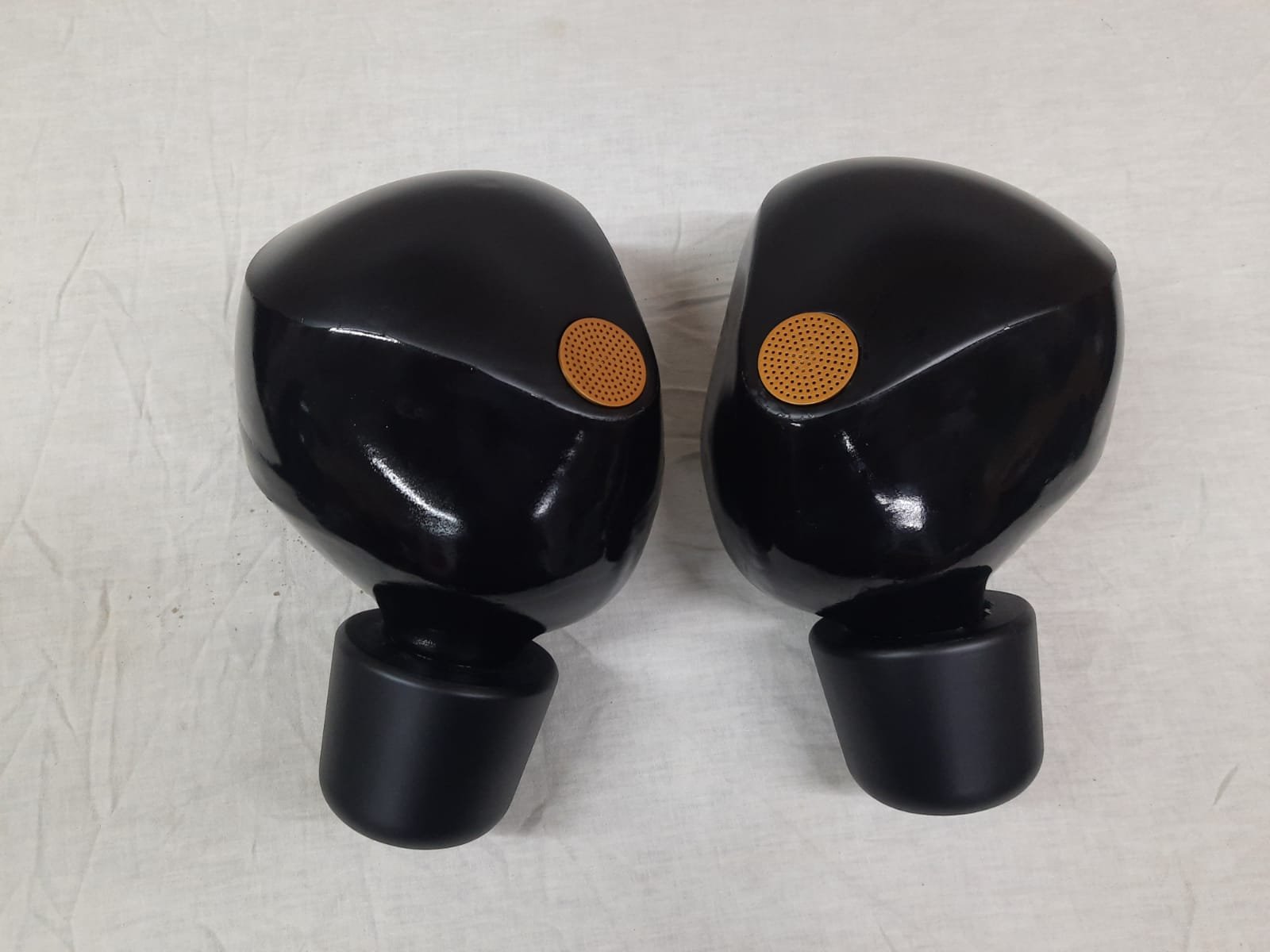 Pair of black wireless earbuds on a white surface