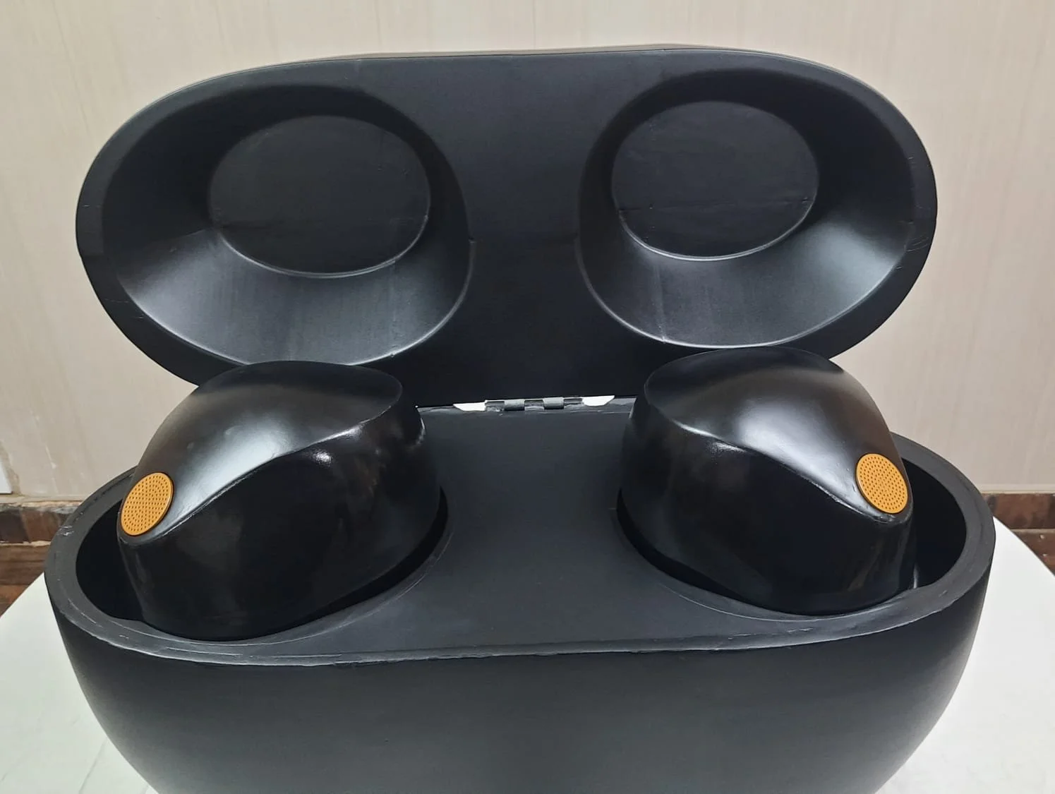 Black sculptural container with two rounded compartments and an orange accent inside.