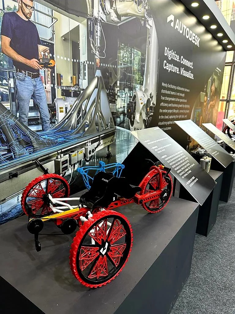Exhibit of a model car at Autodesk booth, featuring futuristic design and advanced technology concepts, with digital projection in the background.
