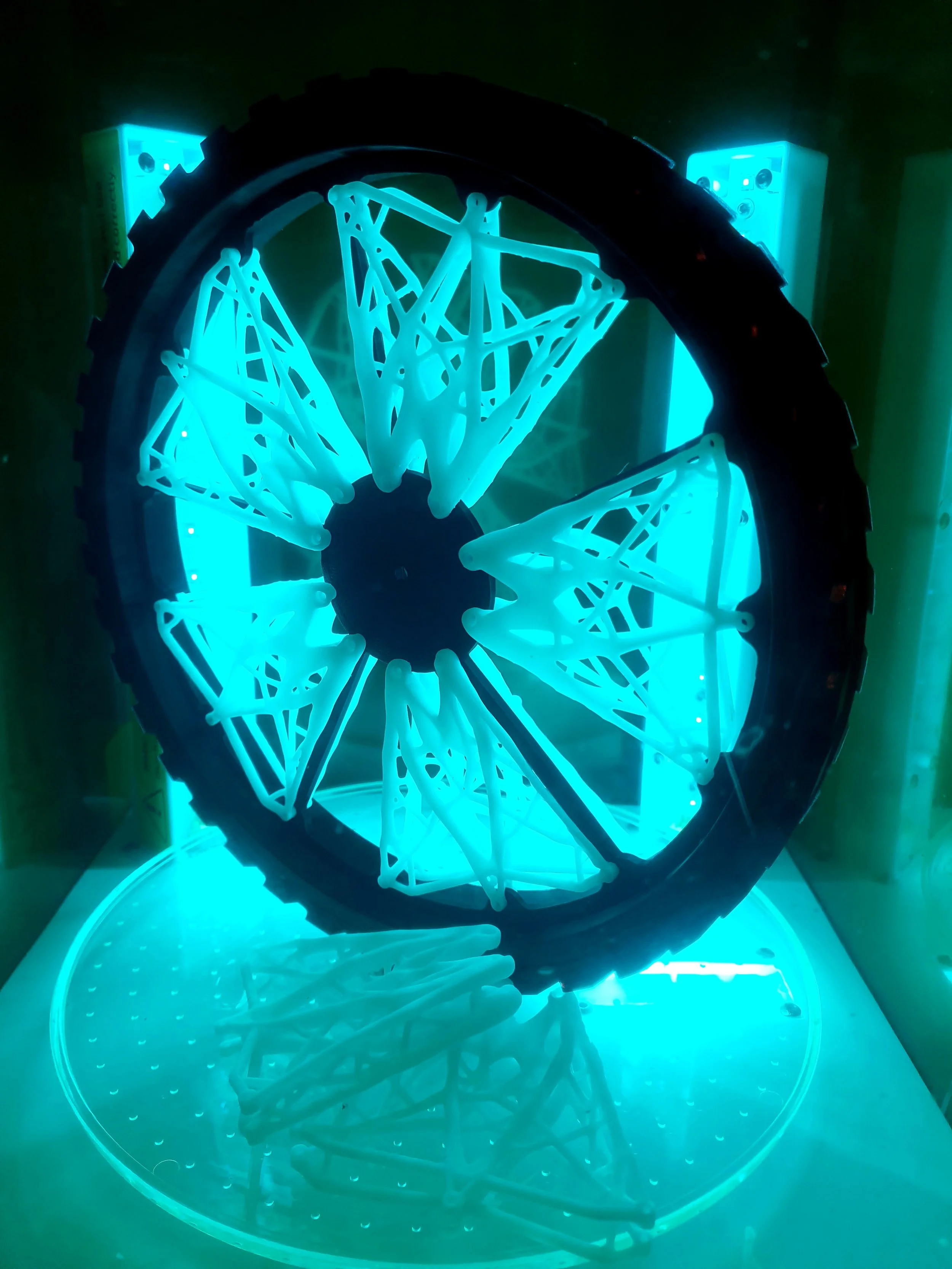3D-printed wheel with intricate lattice structure under blue LED light