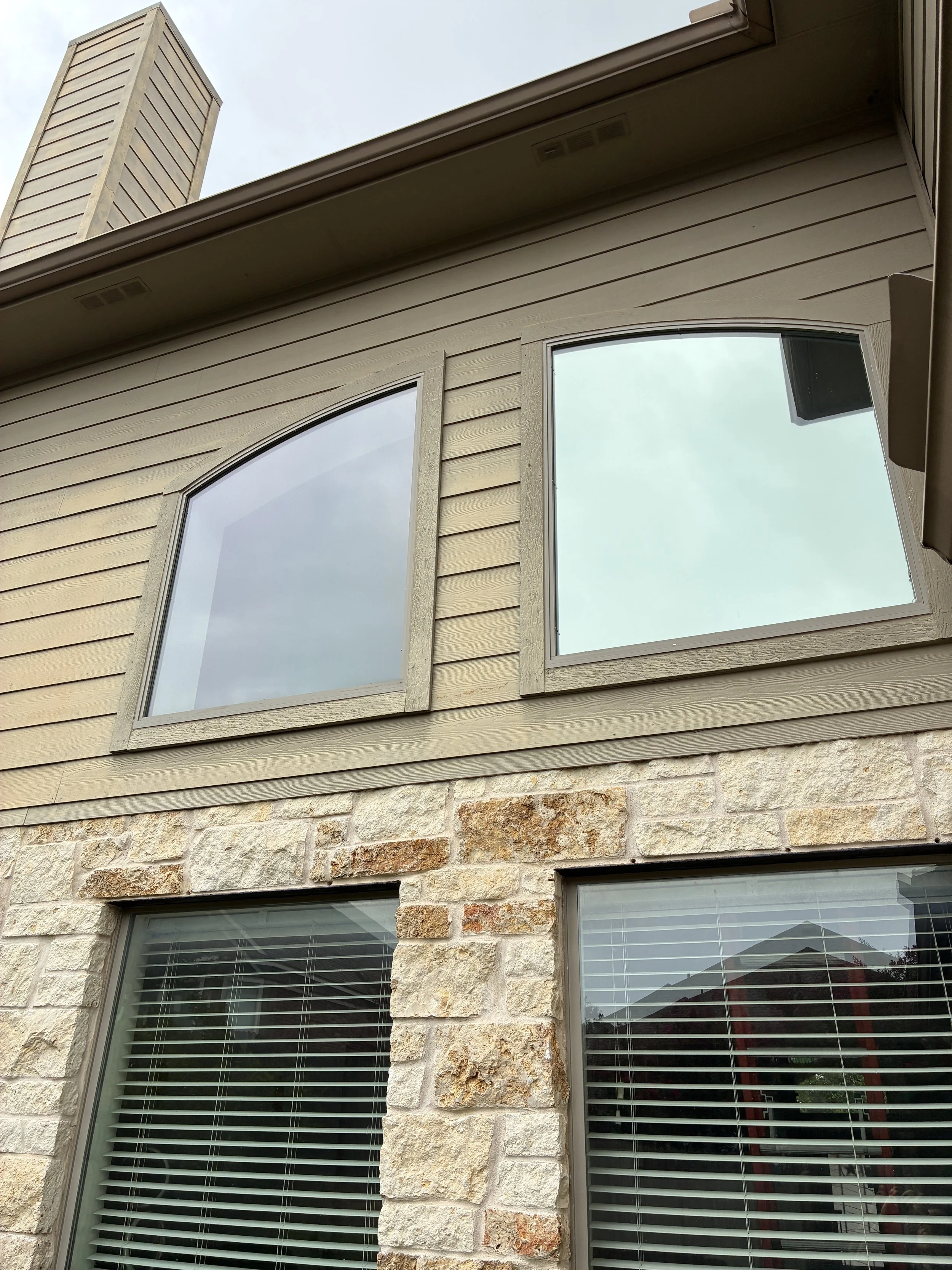Two story stone home in Cedar Park TX with residential window film installed