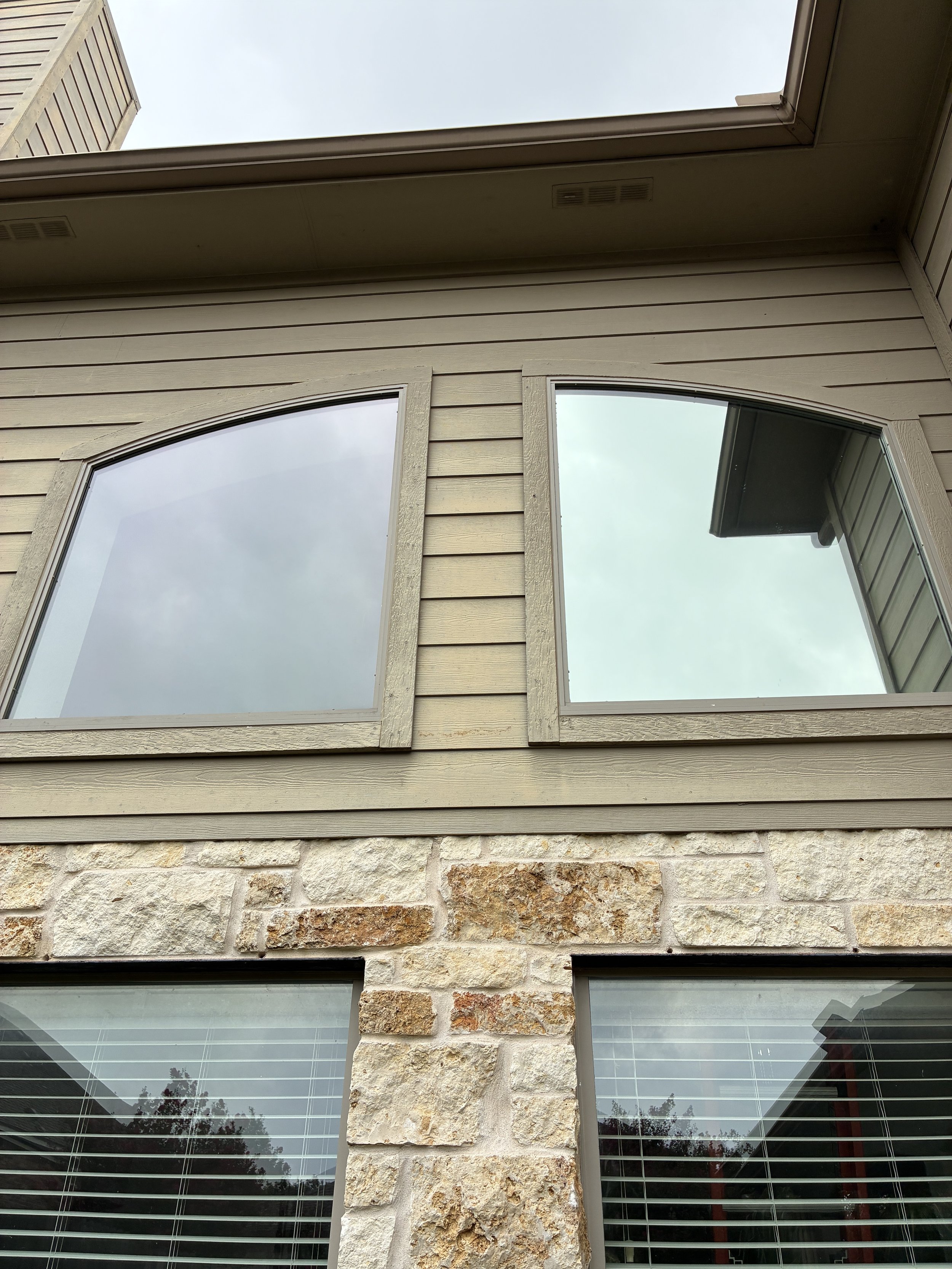Close up of tinted arched windows on stone home exterior
