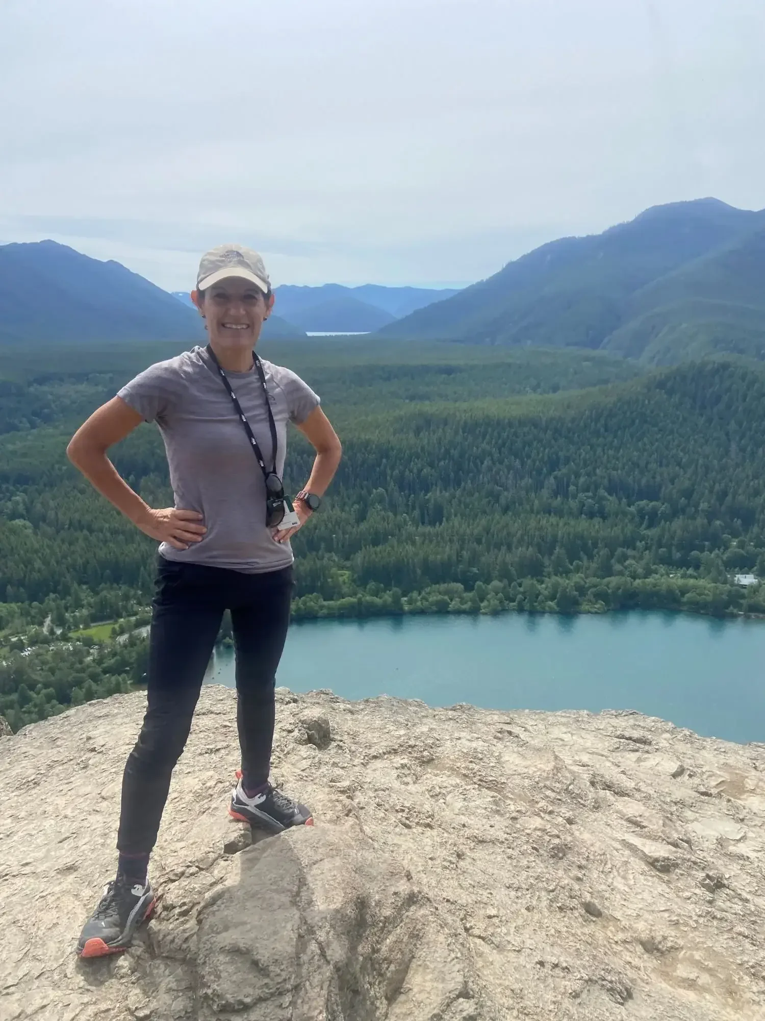 Susie Klein running coach standing on rocky summit with mountain lake view