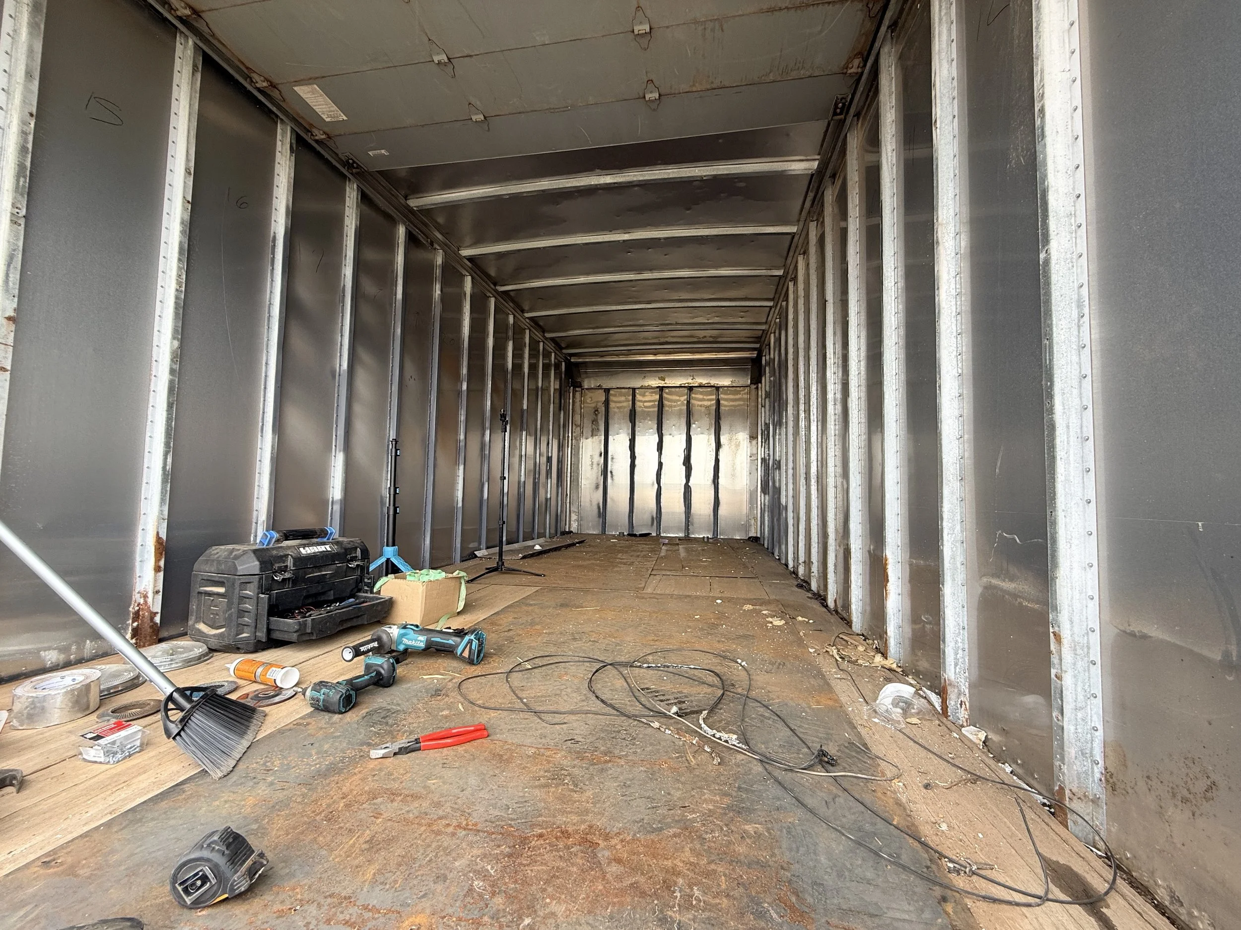 The interior of a partially constructed or renovated room with metal framing, scattered tools, and debris on the floor.