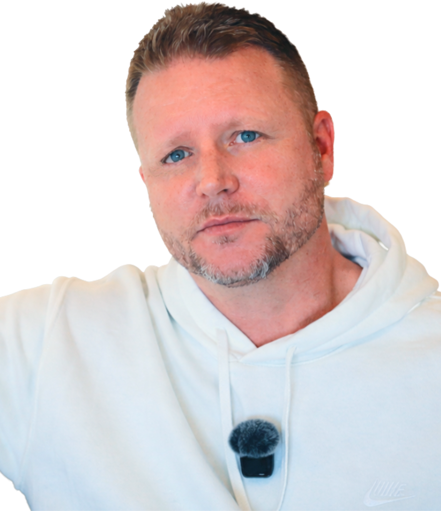 A man with short brown hair, blue eyes, and a beard, wearing a white hoodie, is looking at the camera with a neutral expression.