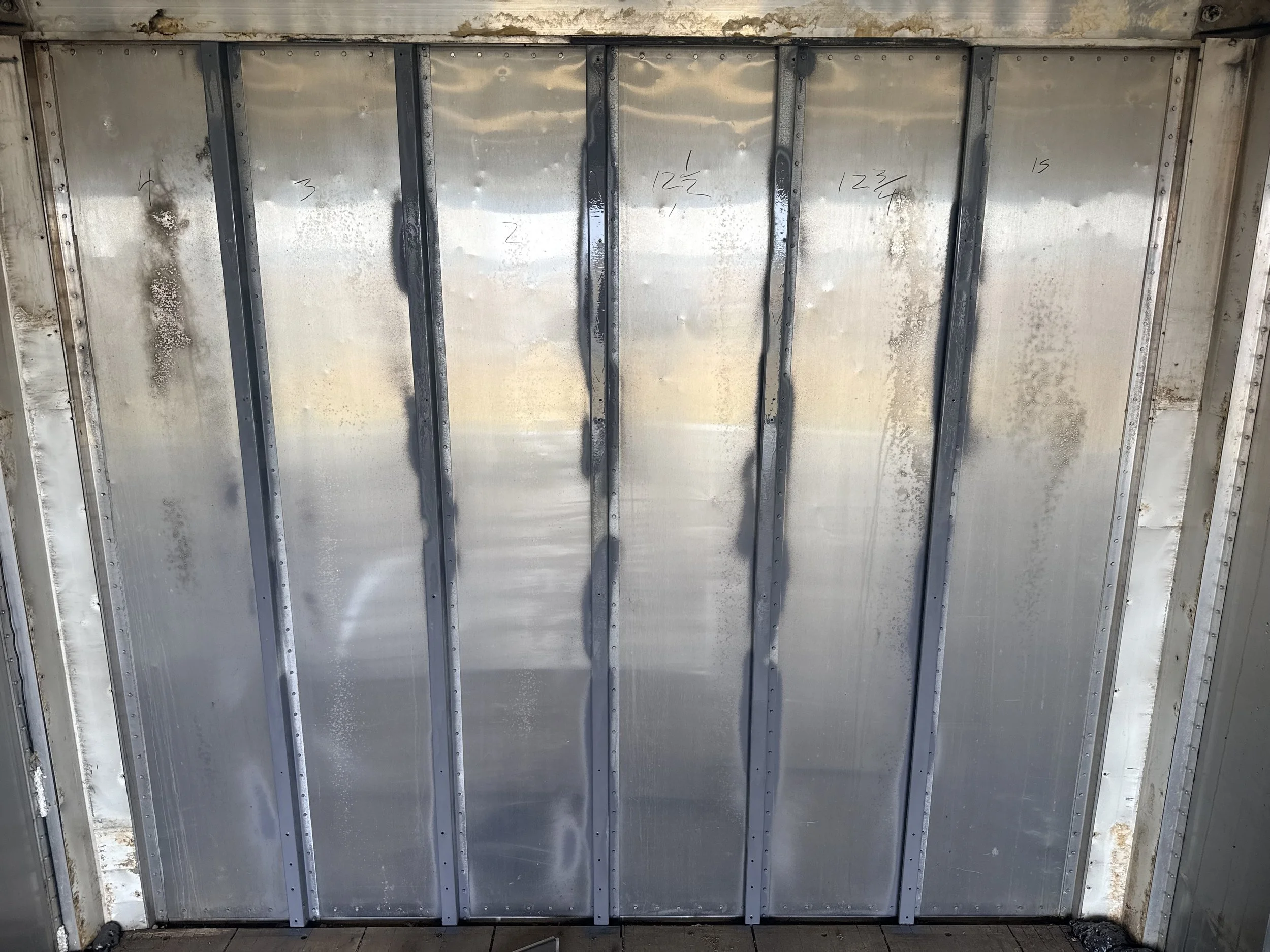 Metal ceiling with black metal beams and handwritten numbers.