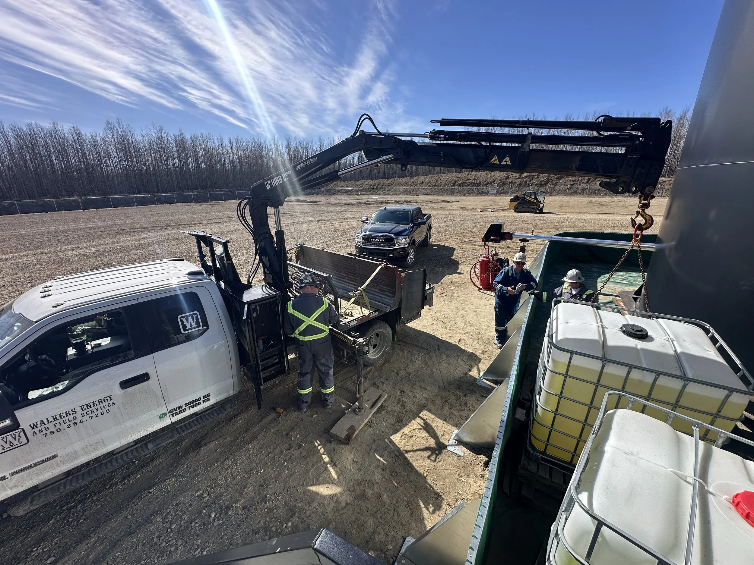 Construction workers working with equipment at a construction site under a blue sky with wispy clouds