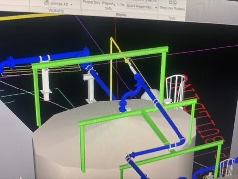 3D computer model of an industrial piping system with green, blue, and white pipes and support structures.