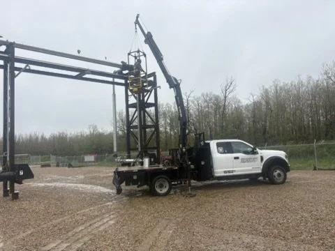 Construction truck with a crane on a dirt surface during an overcast day.