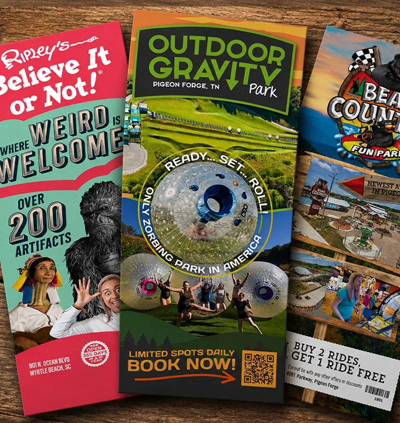Brochures for outdoor attractions including Ripley's Believe It or Not!, Outdoor Gravity Park in Pigeon Forge, Tennessee, and a beach-themed amusement park. The Ripley's brochure mentions over 200 artifacts, and the Outdoor Gravity Park offers bumper Zorbing in a photo showing people on the field.