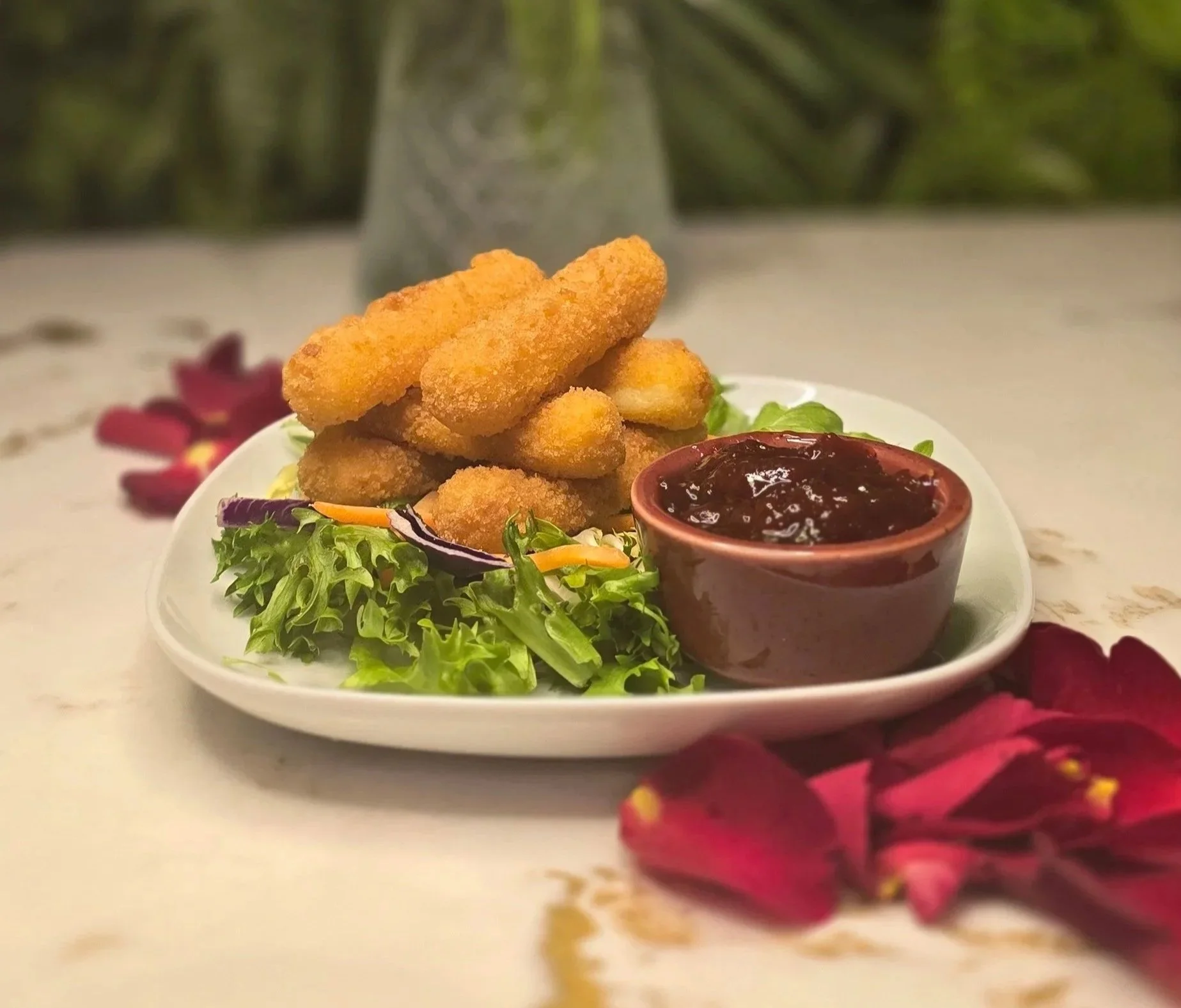 A small plate style of fried mozzarella sticks with salad greens and a small bowl of tomato chutney on a marble table in ninety seven bar Sidcup Kent.