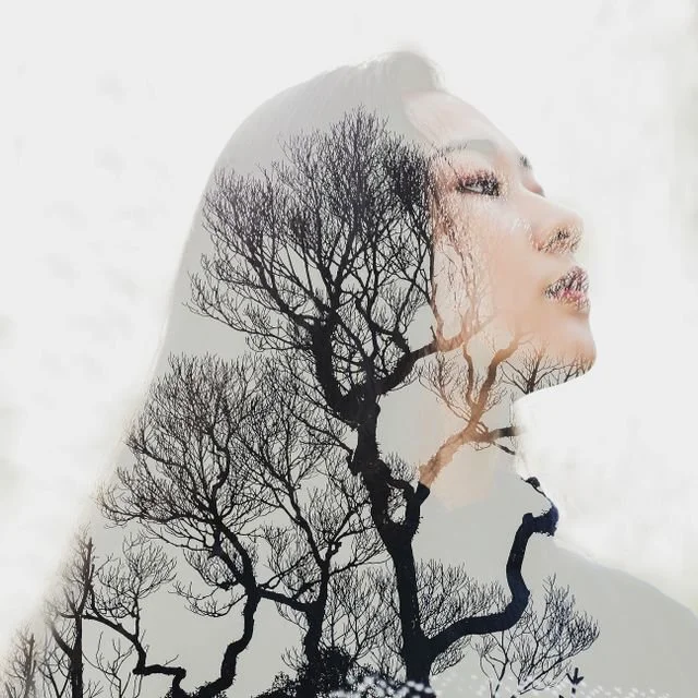double exposure featuring a woman and tree branches