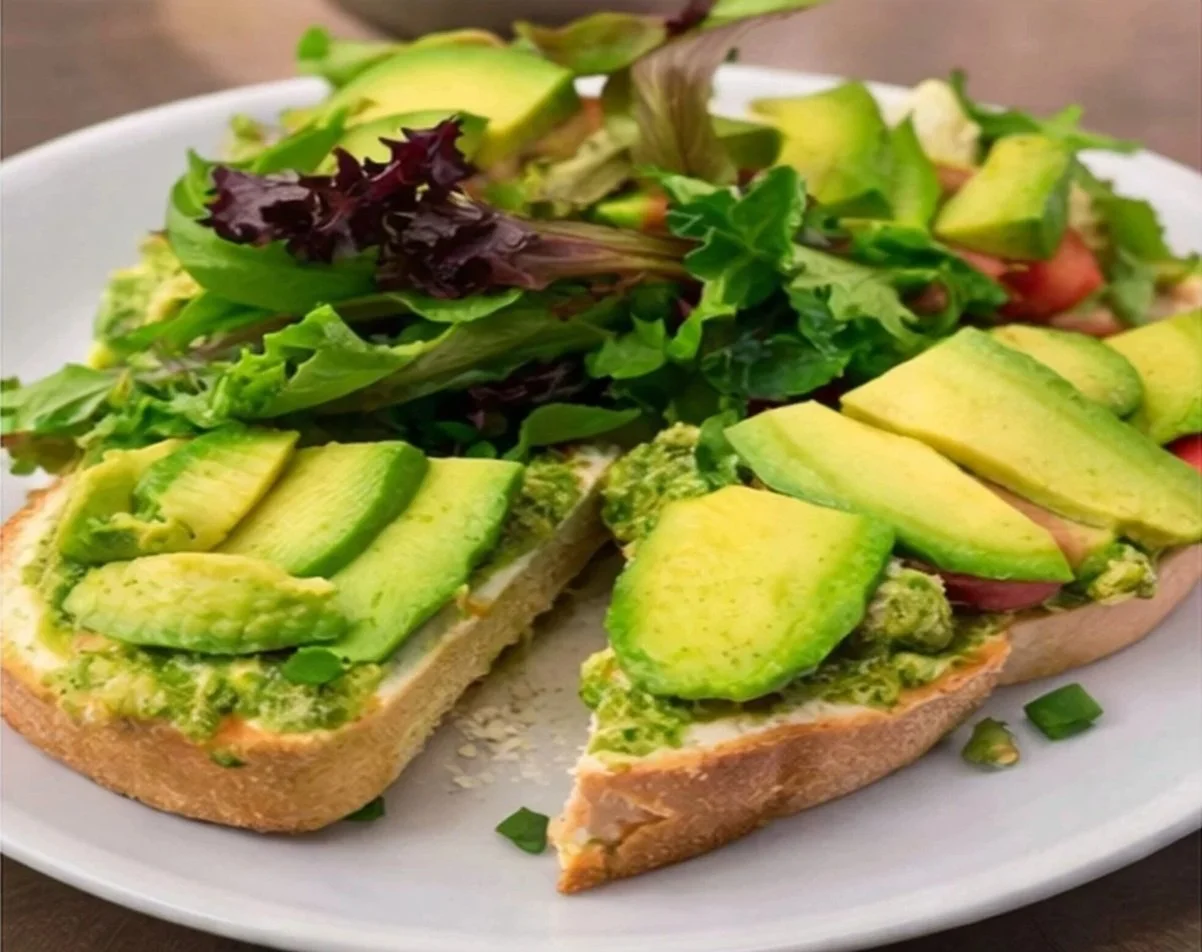 Asparagus and tomato avocado toast with mixed greens on white plate.