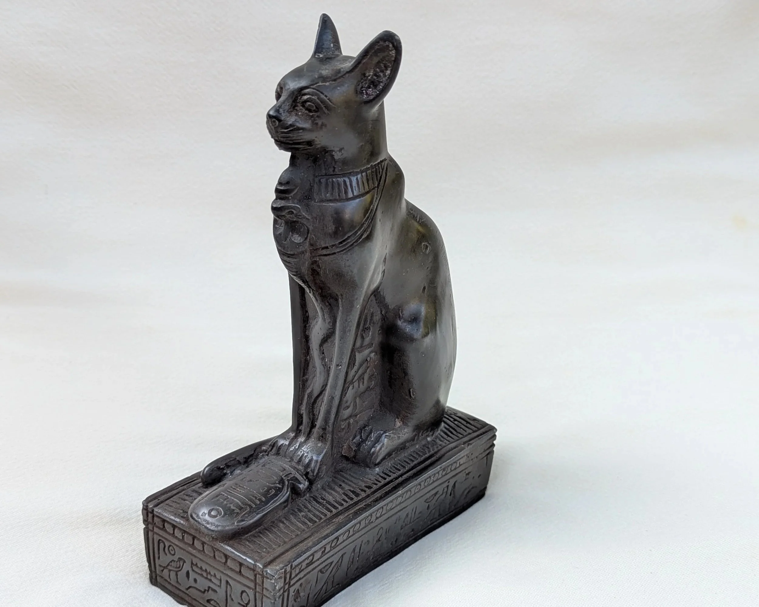 Statue of the Egyptian god Anubis with a jackal head, seated on a decorated base.
