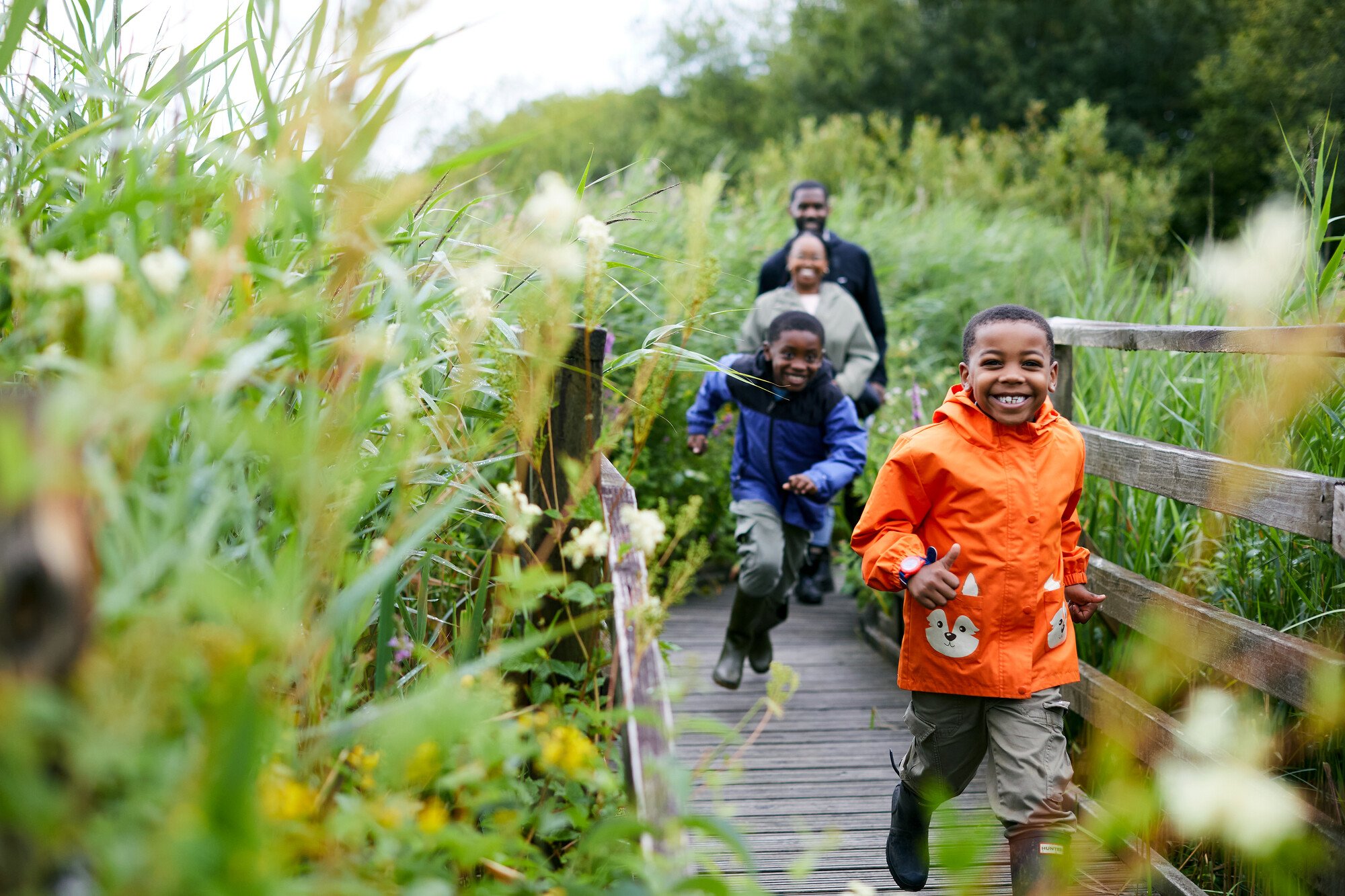 Family running and playing on boardwalk in Wetlands centre.