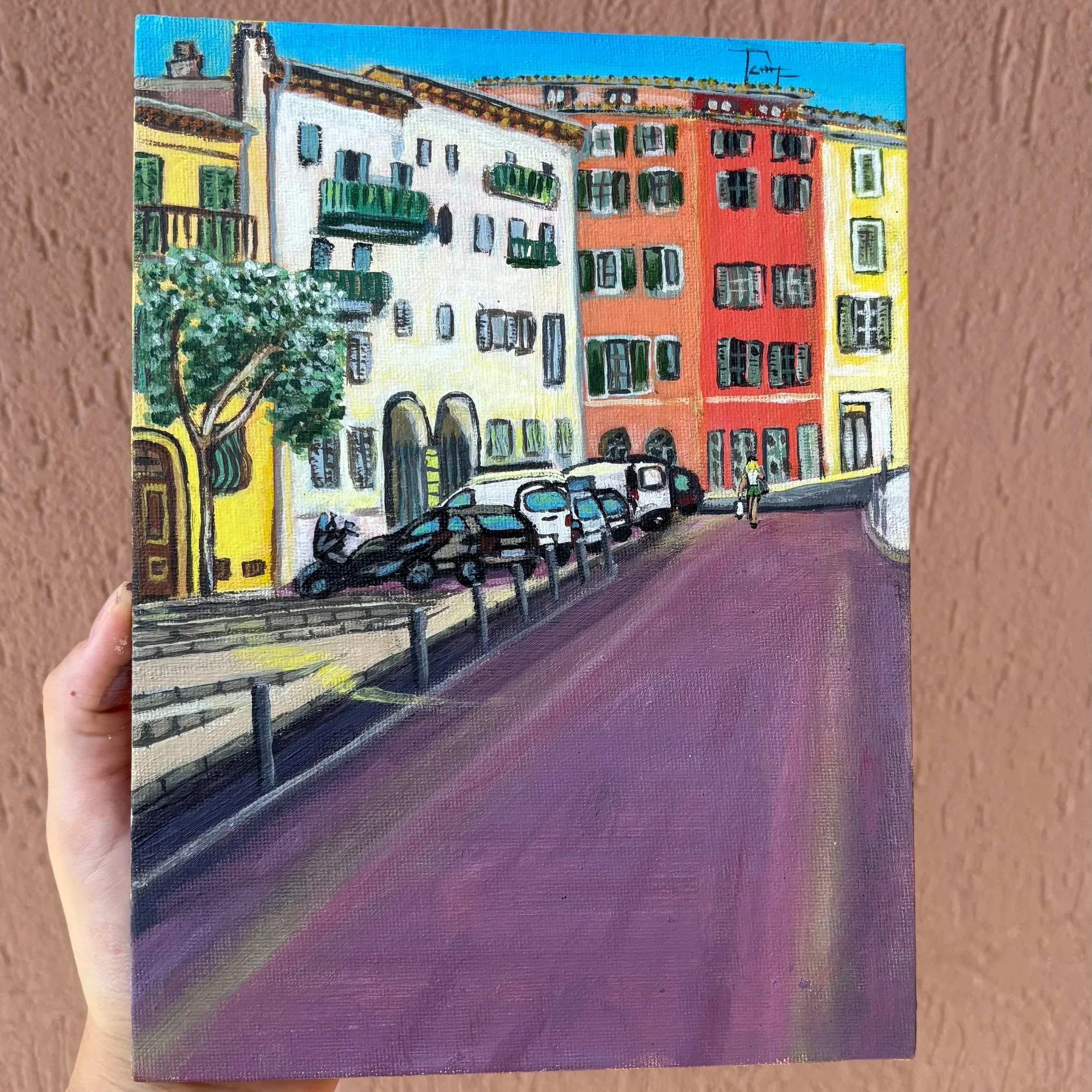 Colorful painting of a city street scene with buildings, cars, a person walking, and trees, featuring bright colors and a lively urban atmosphere.