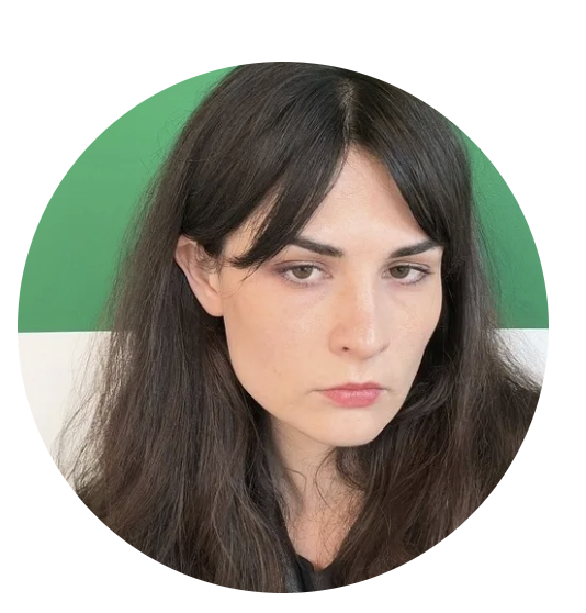 Close-up of a woman with long dark hair and serious expression, against a green and white background.