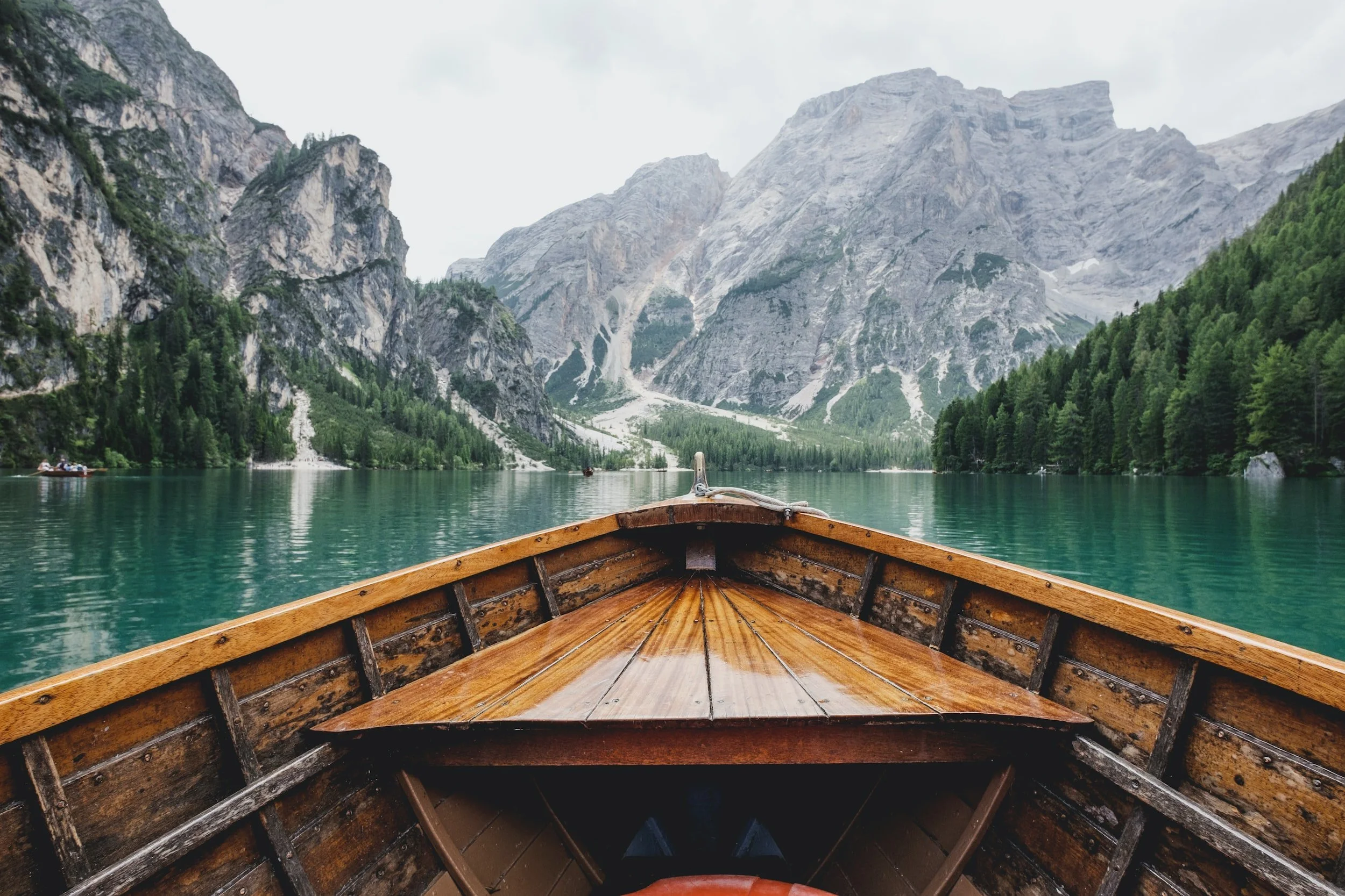View from a boat on a mountain lake, with steep rocky mountains and forested slopes surrounding the water.