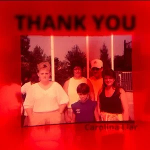 A thank you sign with a photo of five people standing outdoors, with trees and a cloudy sky in the background.