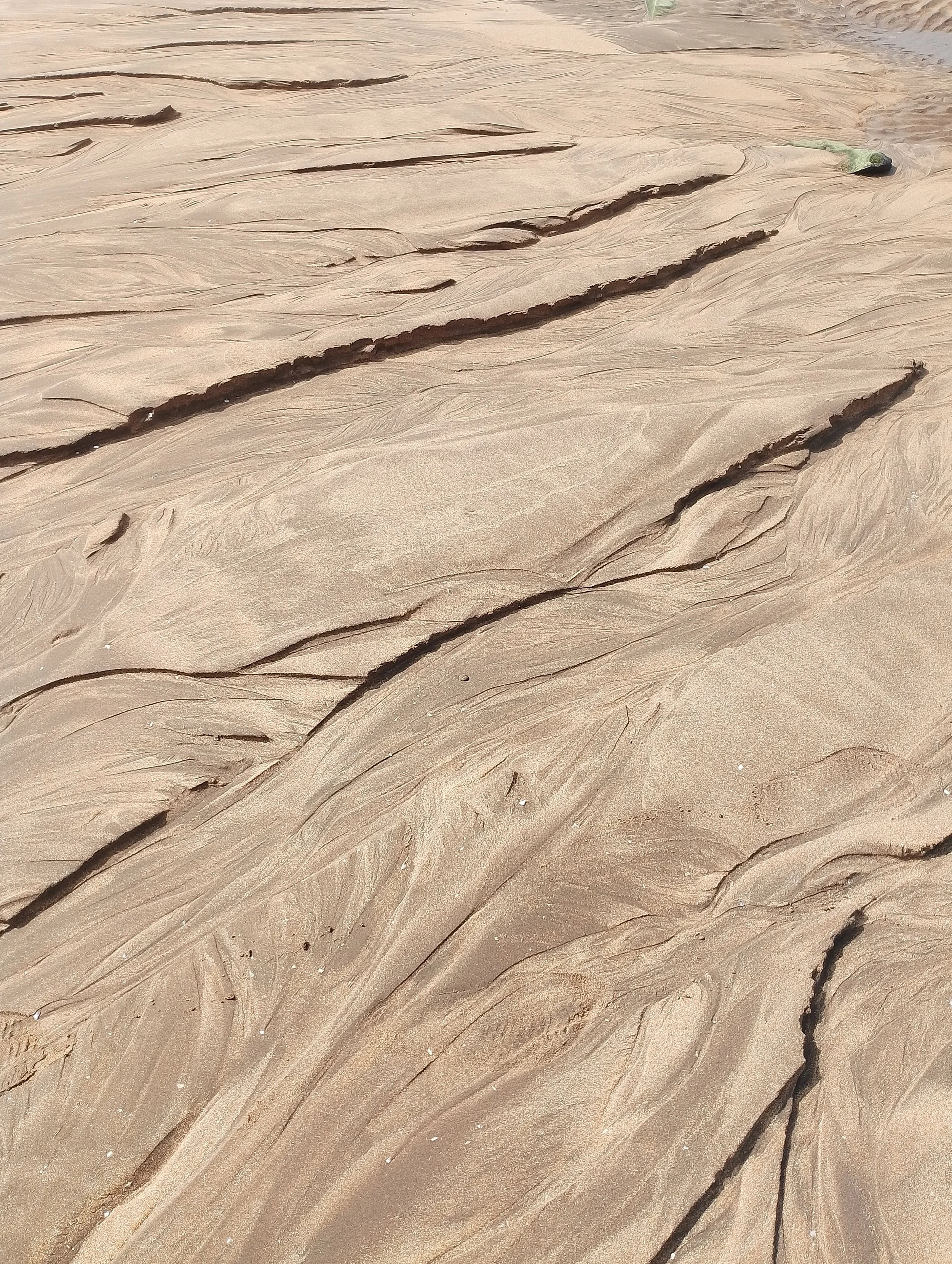 Close-up of textured sand with naturally formed ridges and grooves, possibly near a beach or desert.