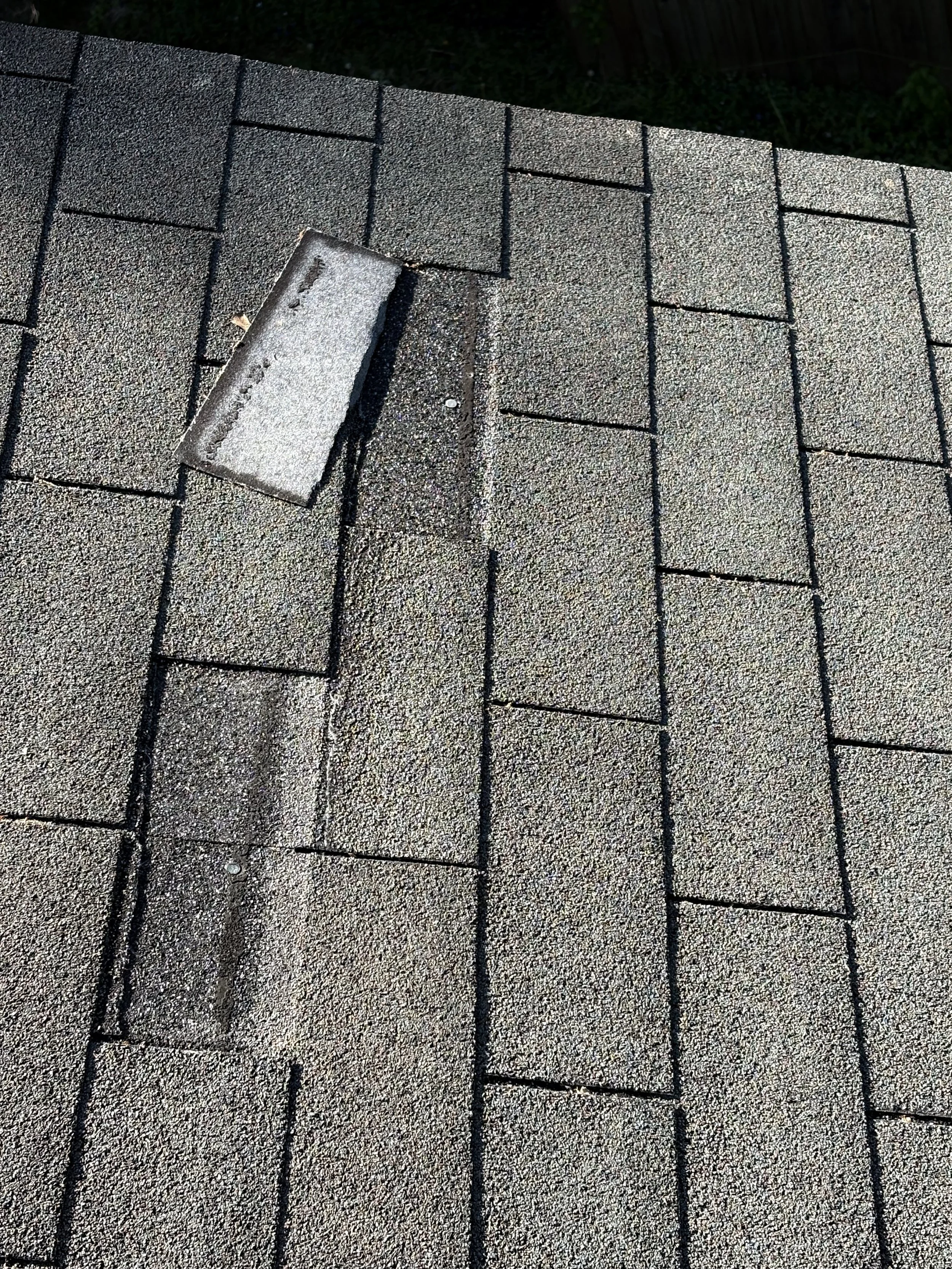 Close-up view of asphalt shingles on a roof with a vent pipe.