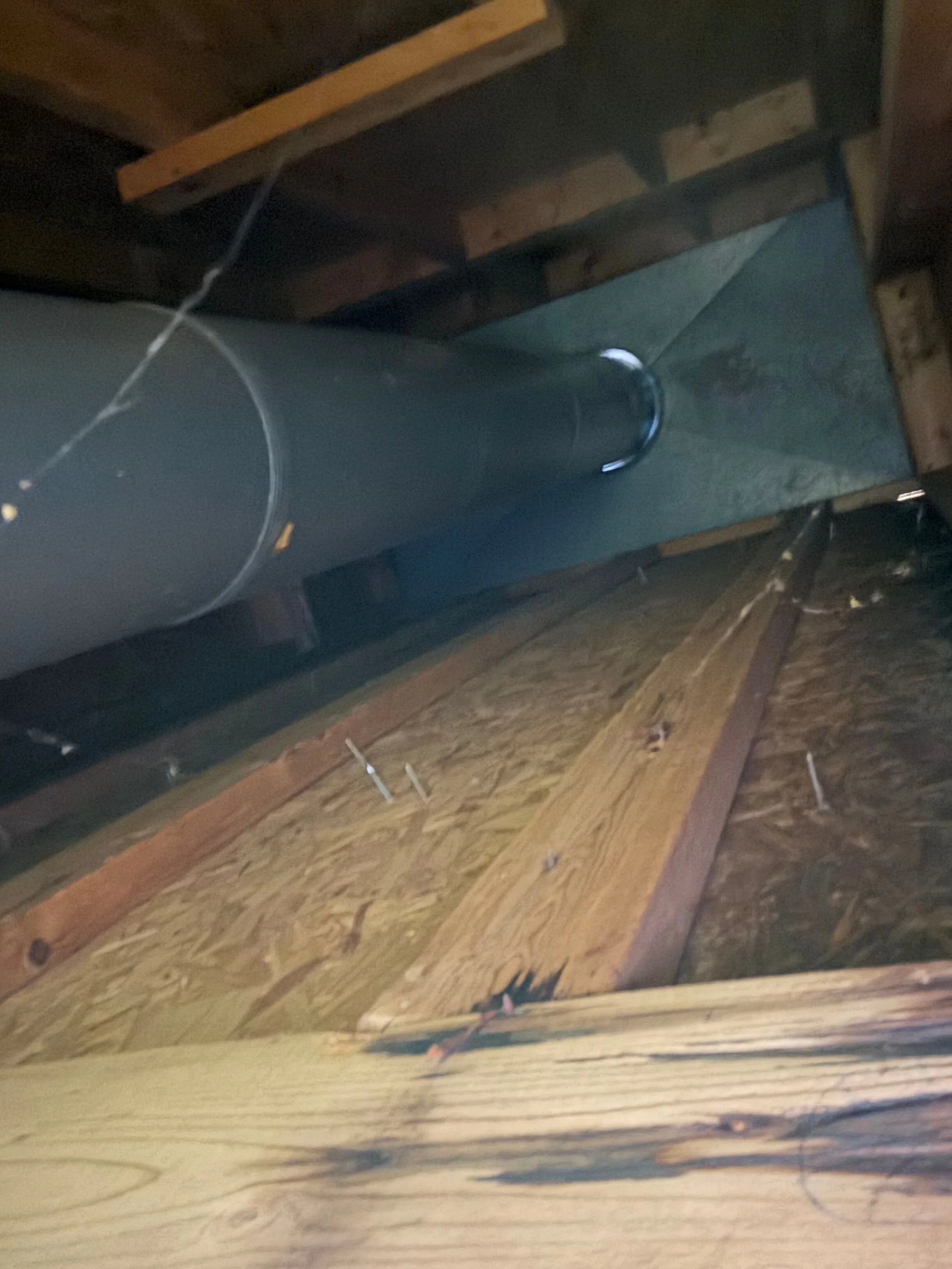 Image of a construction or storage site with wooden shelves, a cylindrical metal pipe, and scattered debris on a wooden surface.