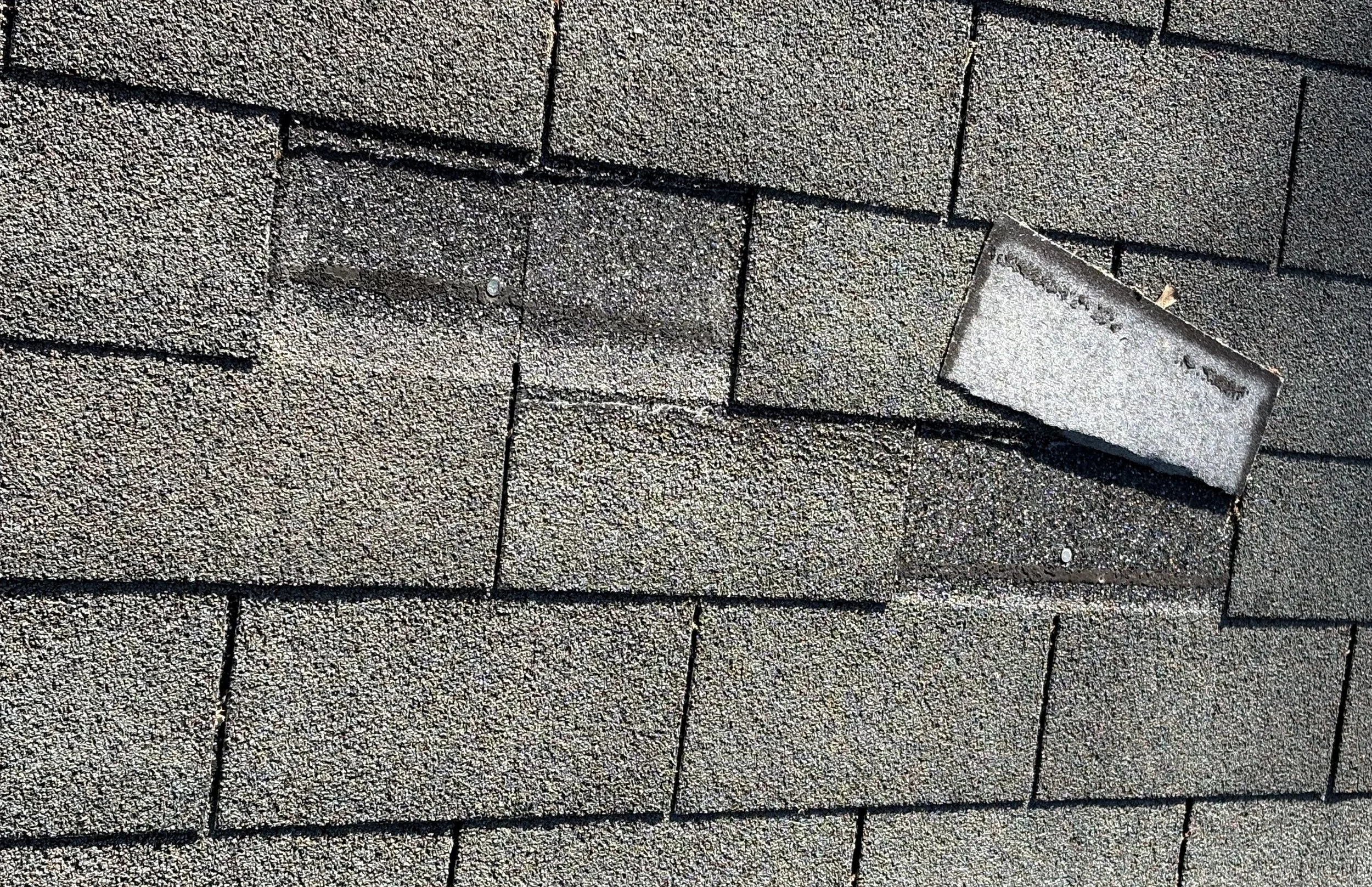 Close-up of a roof's shingles with a roof vent pipe and a vent cap installed.