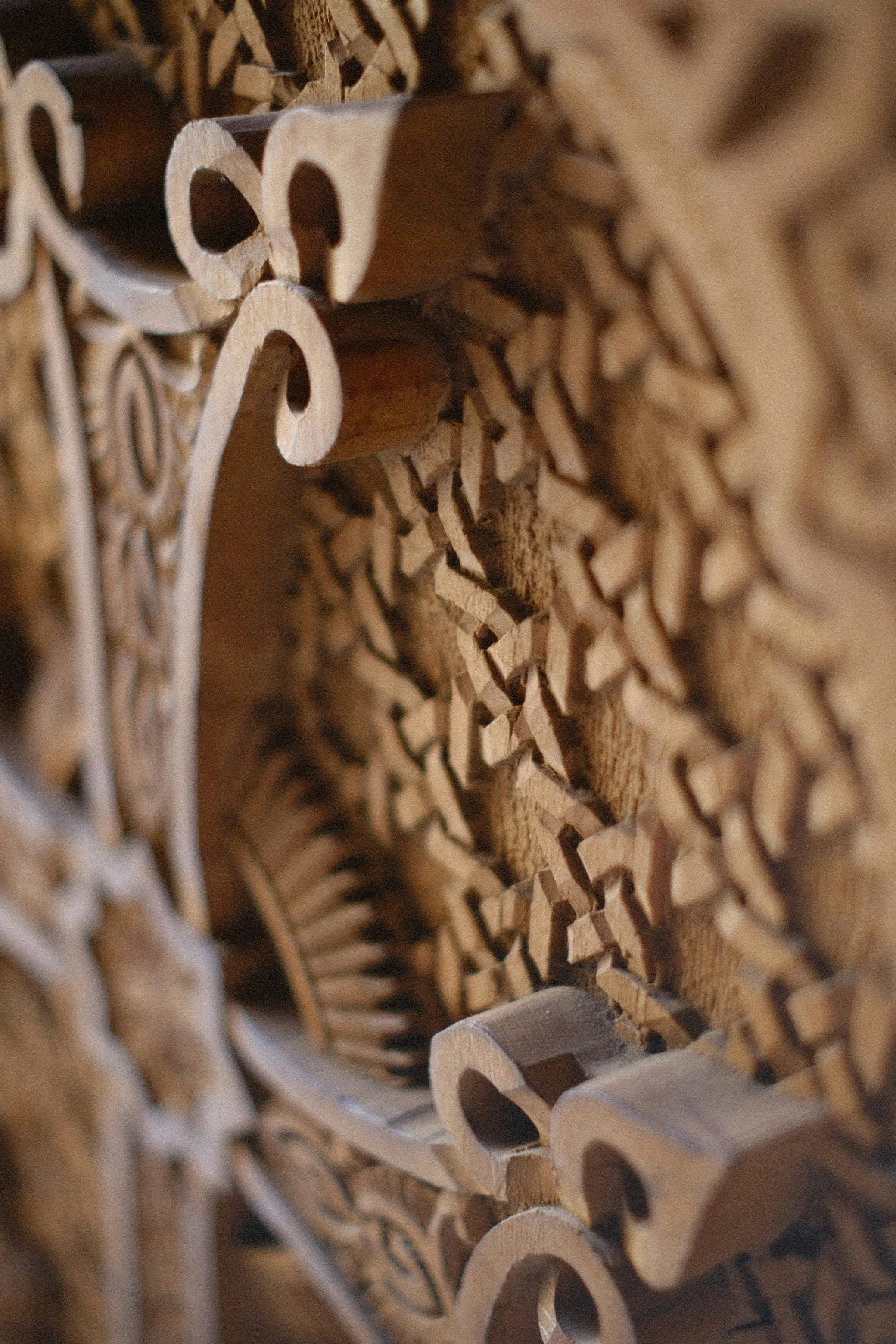 Close-up view of stacked wooden puzzle pieces with intricate designs and holes.