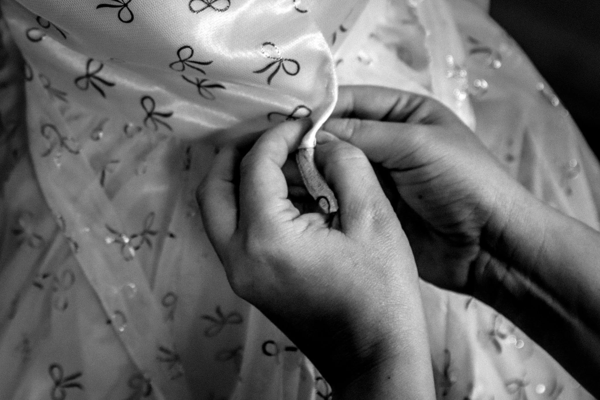 Close-up of hands holding and sewing fabric with bow and polka dot pattern.