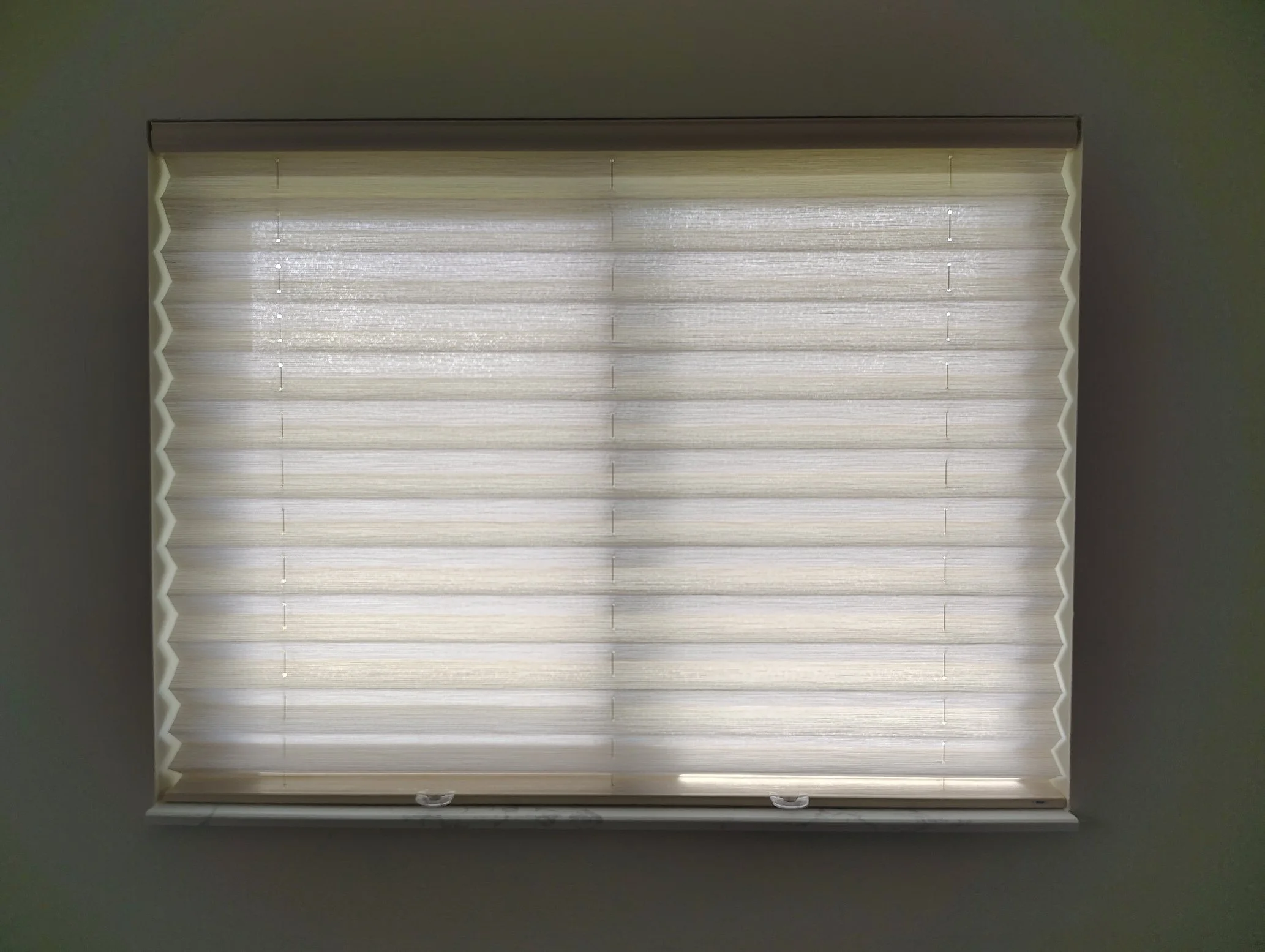 Cream-colored window blind with horizontal slats in a window surrounded by dark gray walls.