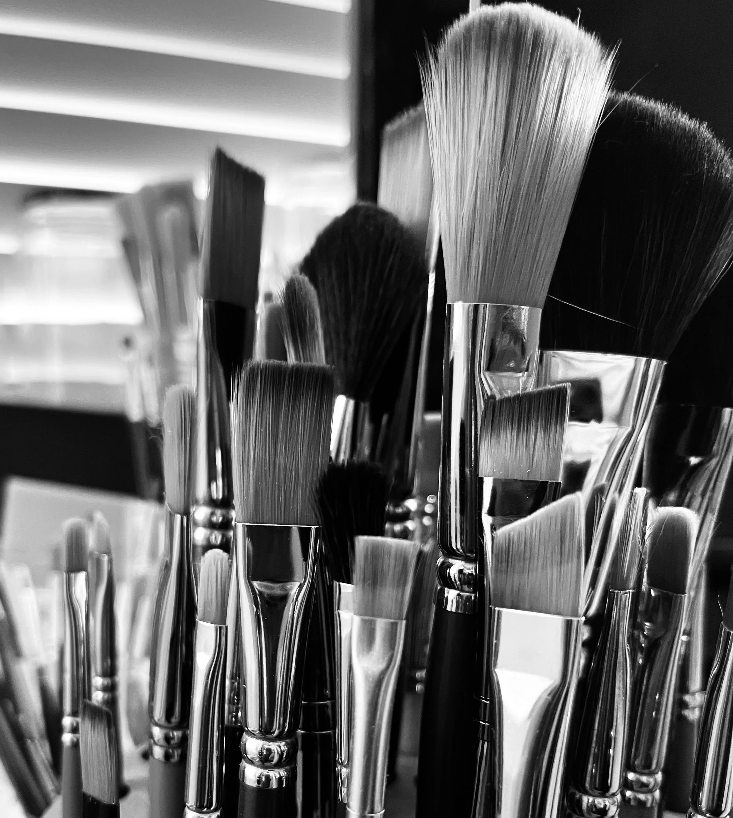 Close-up view of hairbrushes with concentric cylindrical handles, arranged on a reflective surface with a blurred background in black and white.