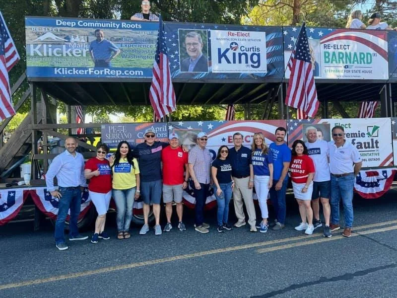 Group of people standing in front of a political float decorated with American flags and campaign banners for Curtis King, Barnard, and other candidates during a parade. The float features campaign posters and a banner with campaign website and candidate information.