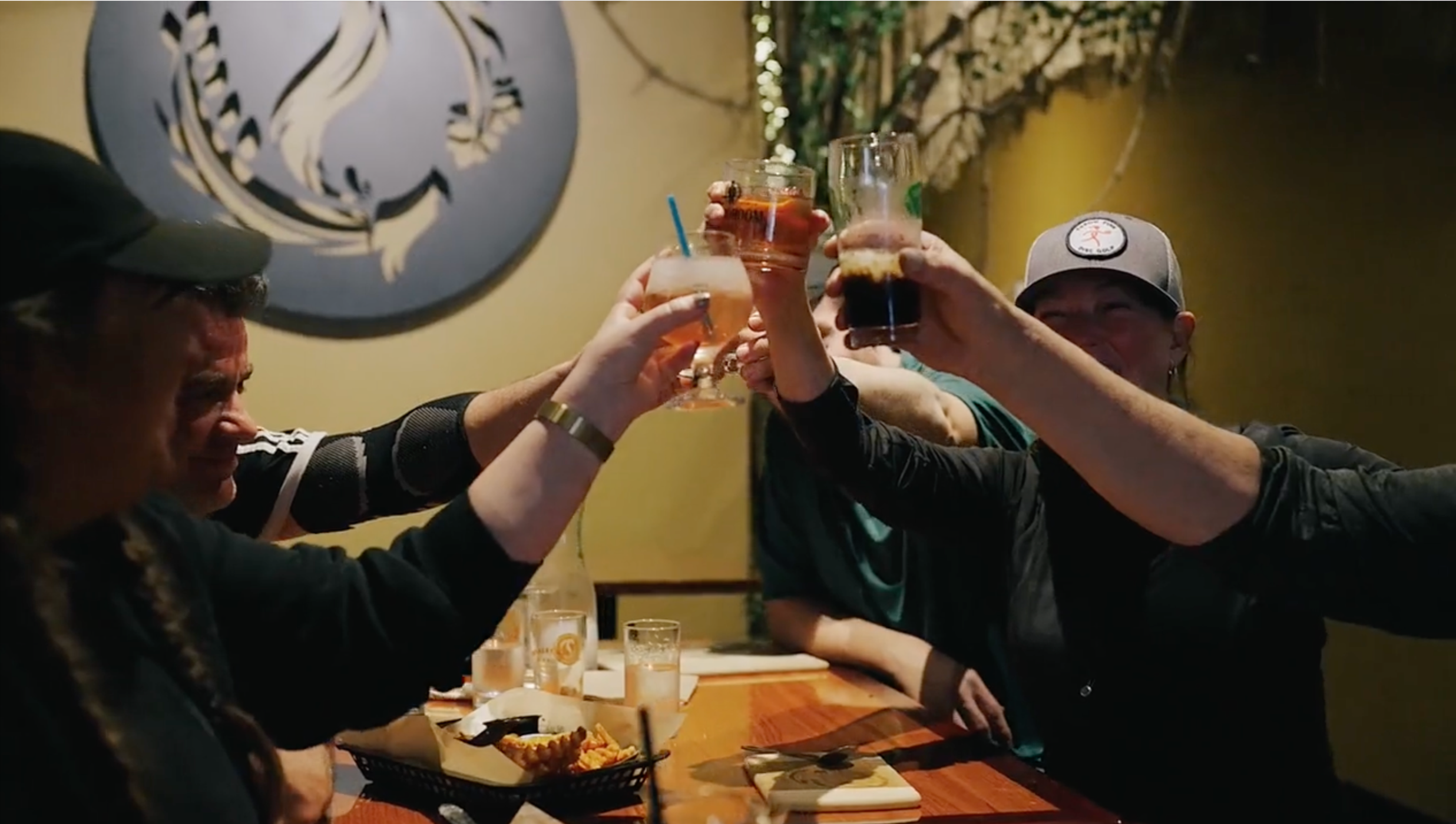 Group of people raising glasses in a toast at a restaurant table.