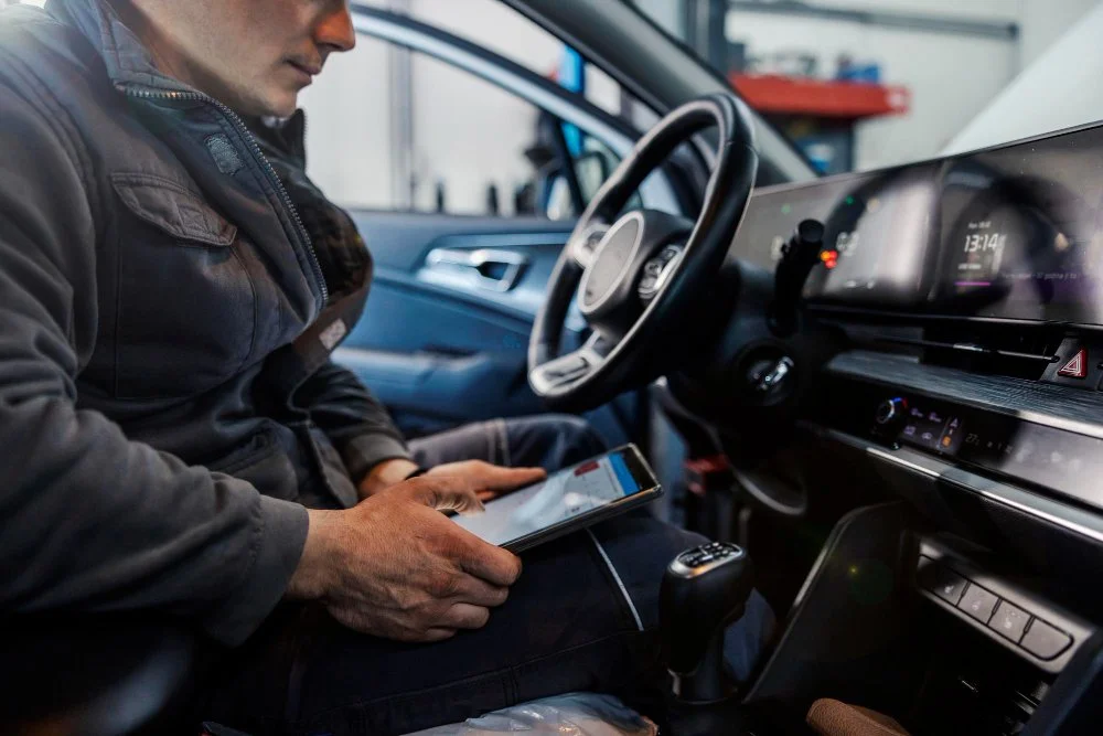 Man sitting inside a modern car, looking at a tablet.