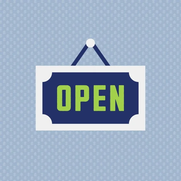 A blue and white sign with the word 'OPEN' in green letters hanging on a wall.