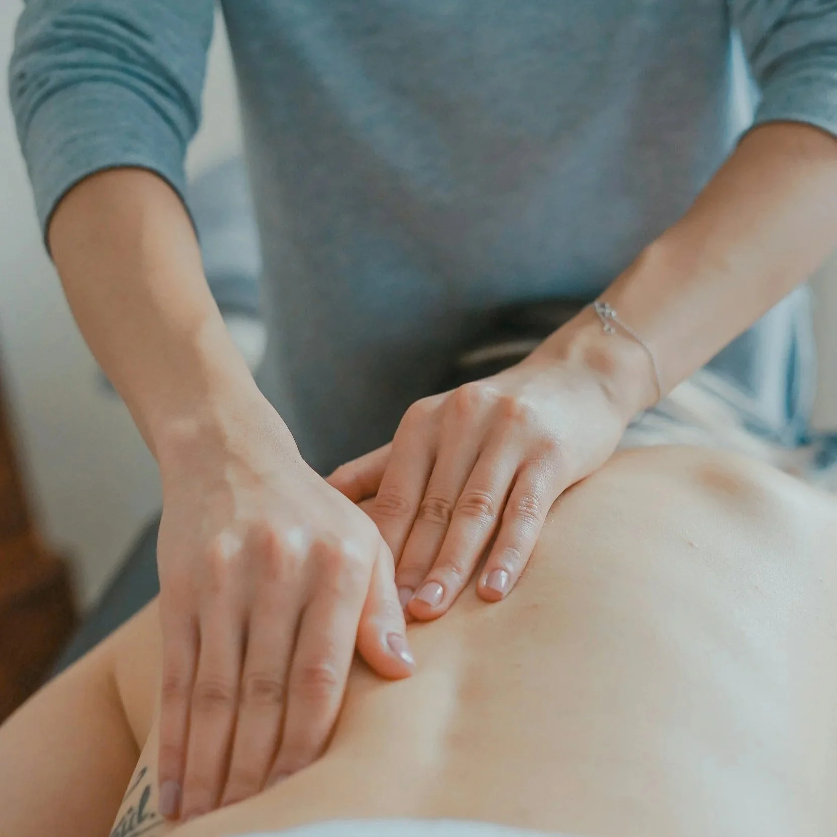 A person receiving a massage, with hands applying pressure on a person's back.