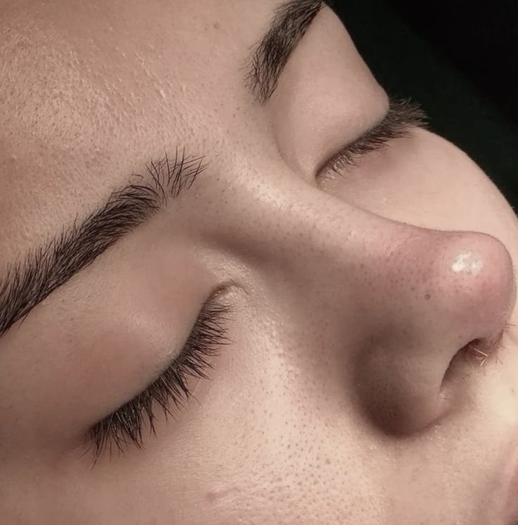 Close-up of a person's face with closed eyes, showing clear skin, eyebrows, and nose.
