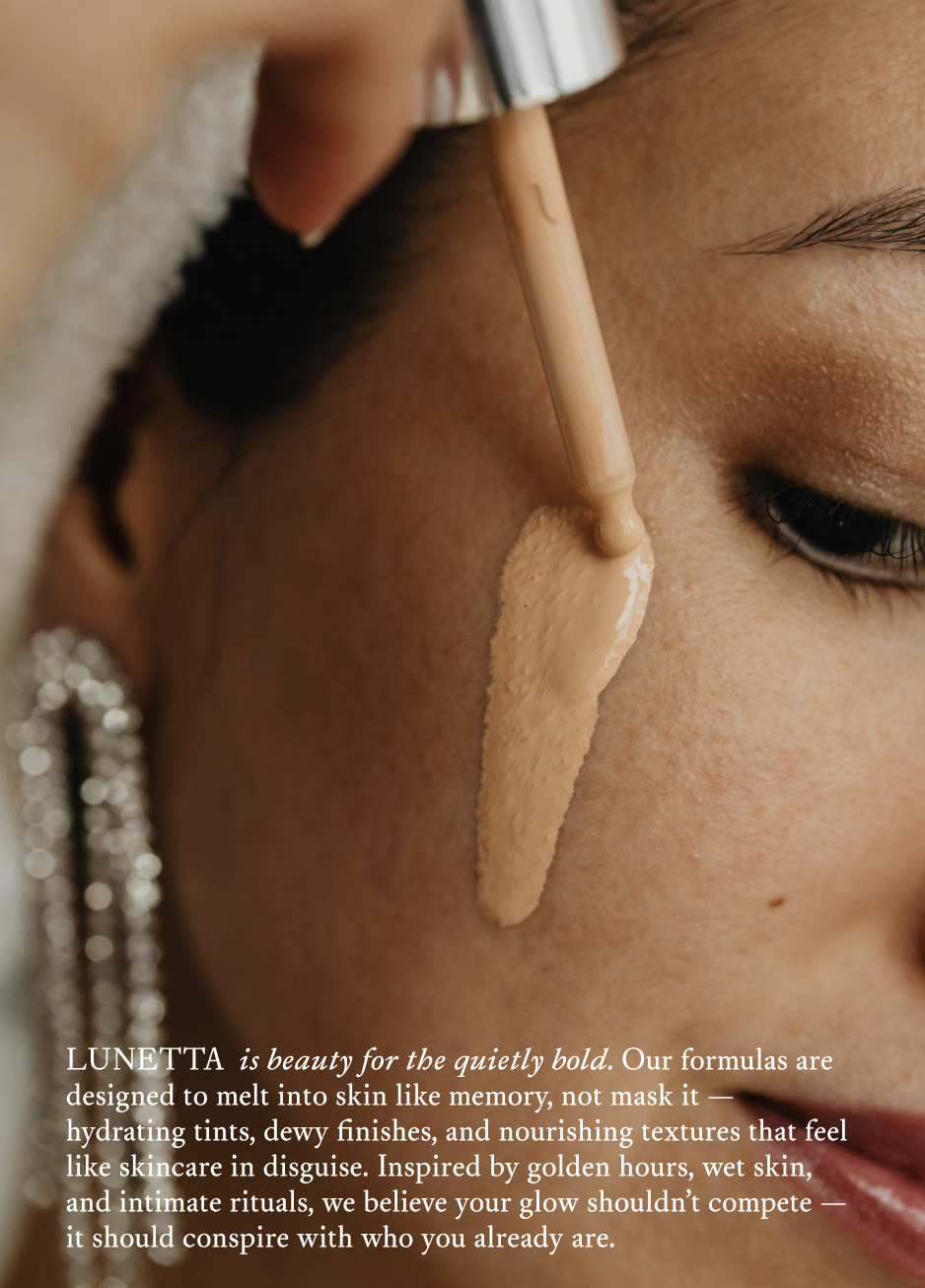 Close-up of a woman applying liquid foundation to her face with a dropper tool, showcasing her skin and grooming details.