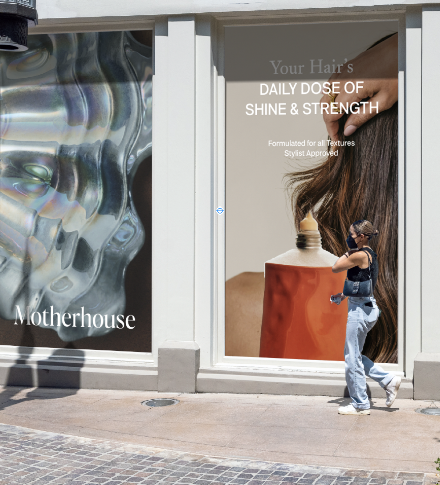 A storefront window display advertising hair care products, with text promoting daily shine and strength for hair, and a woman walking past wearing a face mask, sunglasses, black sleeveless top, and light blue jeans.