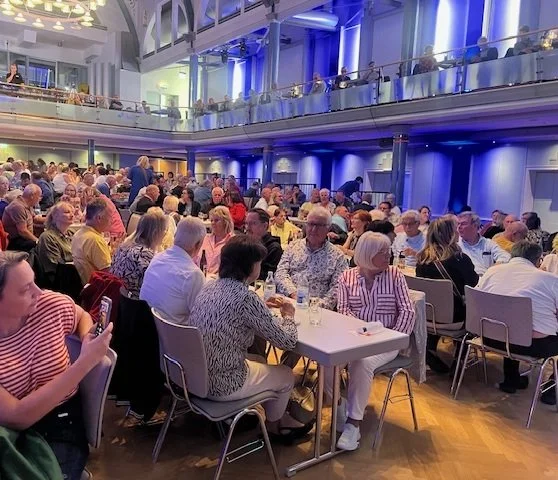 Eine Halle mit vielen voll besetzten Tischen.