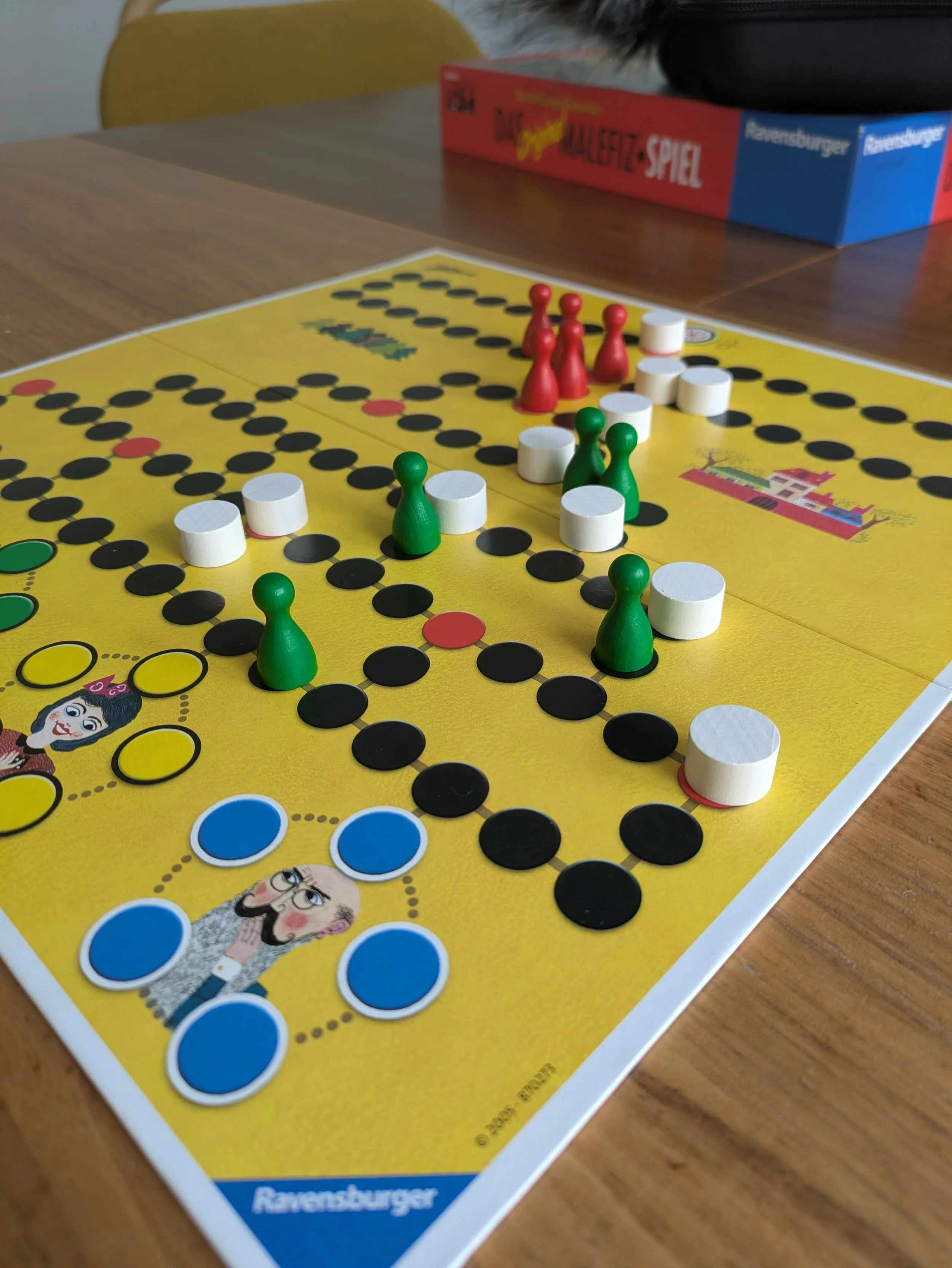 Das Brettspiel Malefiz mit einem gelben Spielbrett und Spielfiguren in verschiedenen Farben.