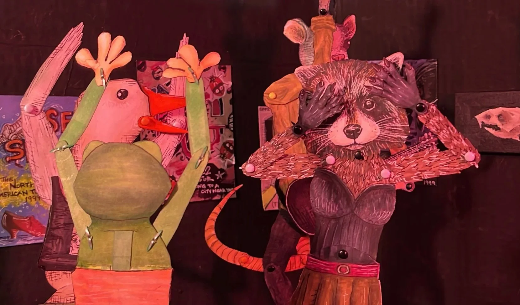 A frog, duck, raccoon, and rat, dance wildly. They are 2-D paper dolls with brad joints. They a