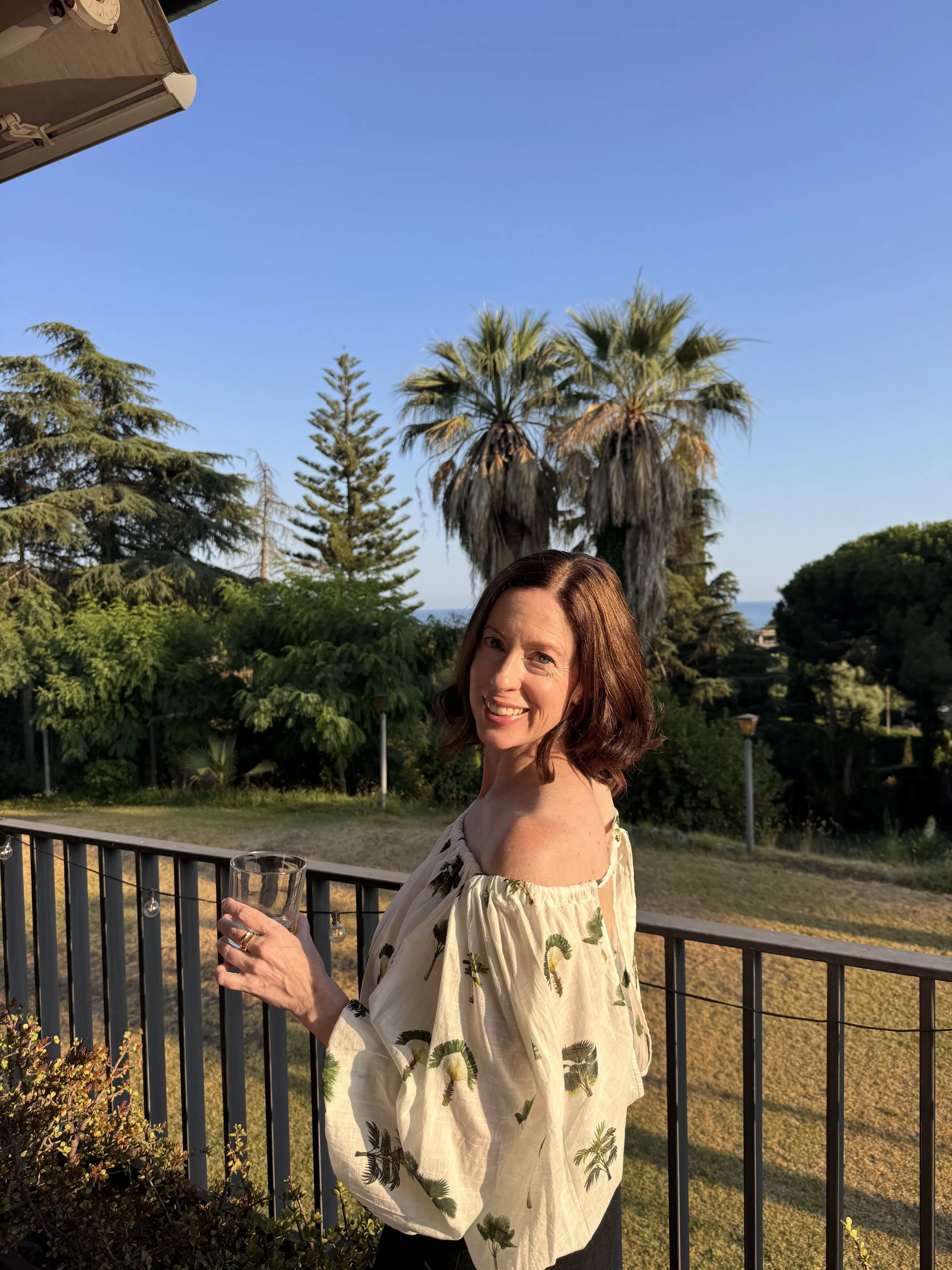 Shay Palms founder styled in a Celandine palm print top with tropical foliage and rooftop views