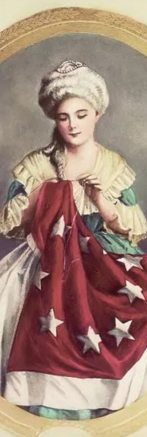 Portrait of a young girl dressed in historical clothing, holding a flag with stars, wearing a white bonnet, and standing against a plain background.