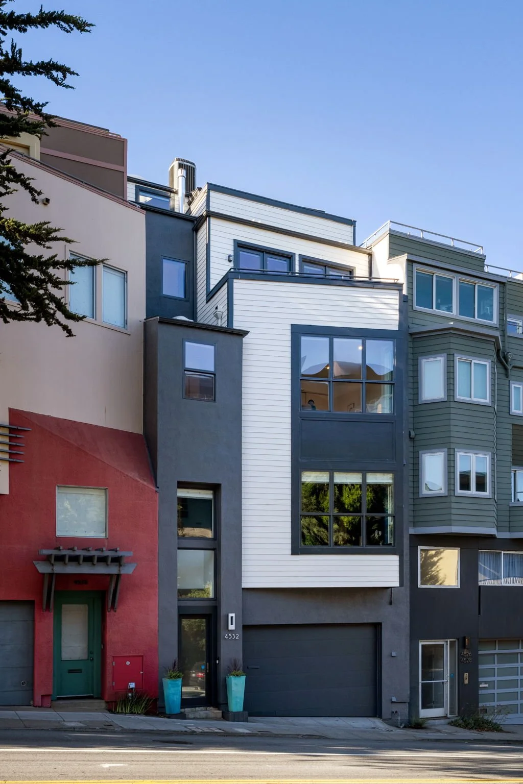 Modern multi-story residential building with colorful facades and large windows under a clear blue sky.