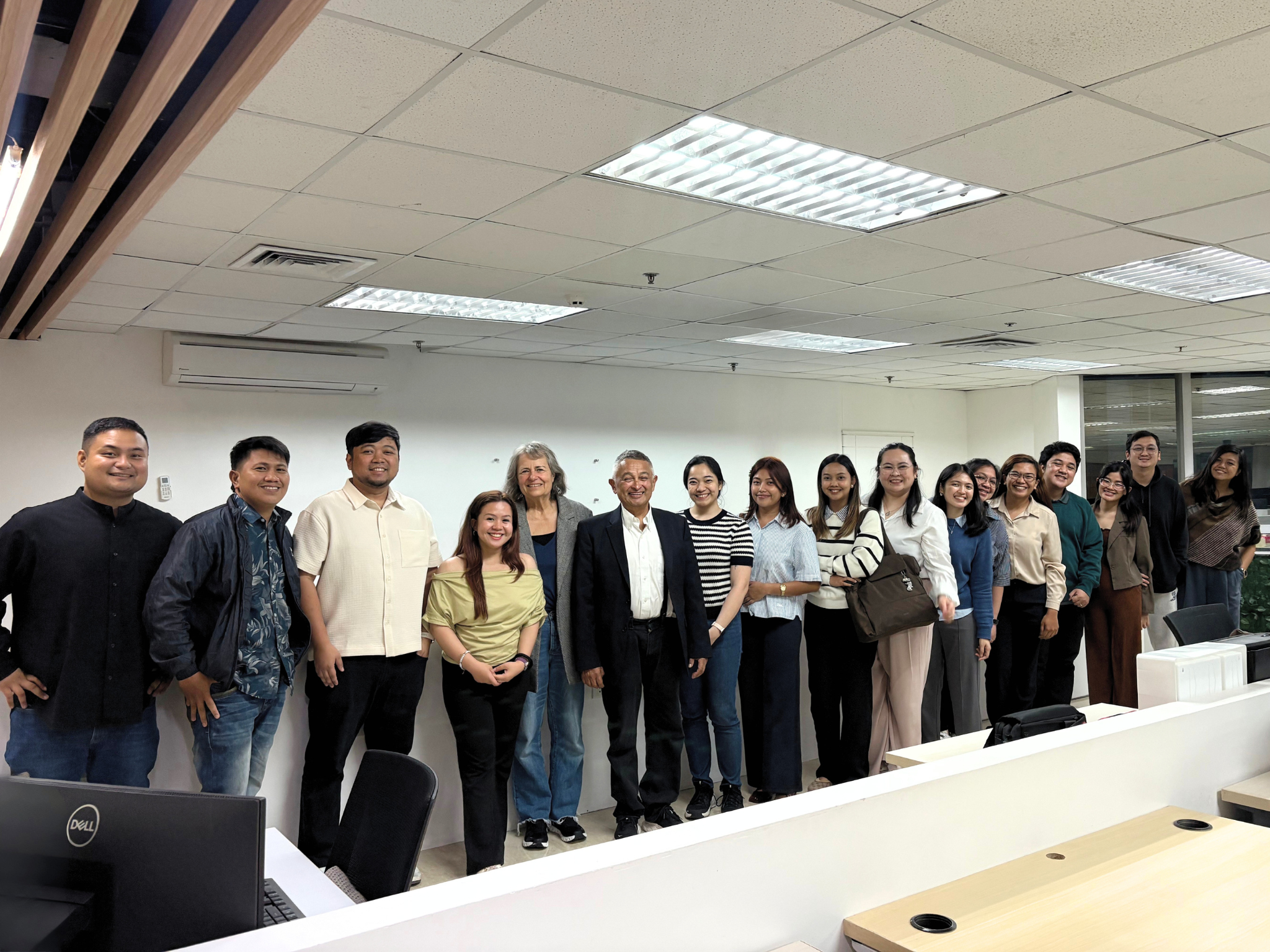 Group of people standing together in an office conference room, smiling for a photo.