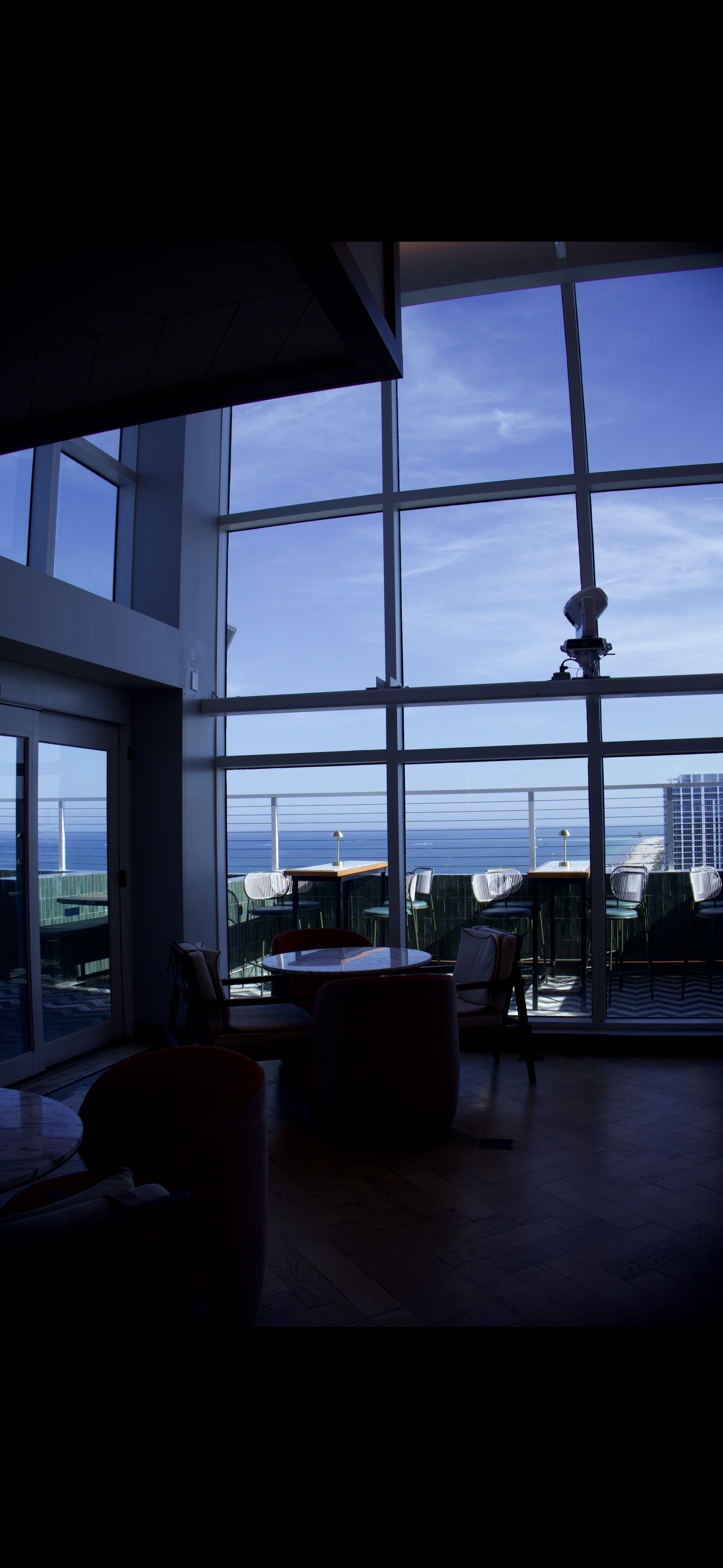 Waterfront dining space with floor to ceiling windows and scenic hospitality atmosphere.