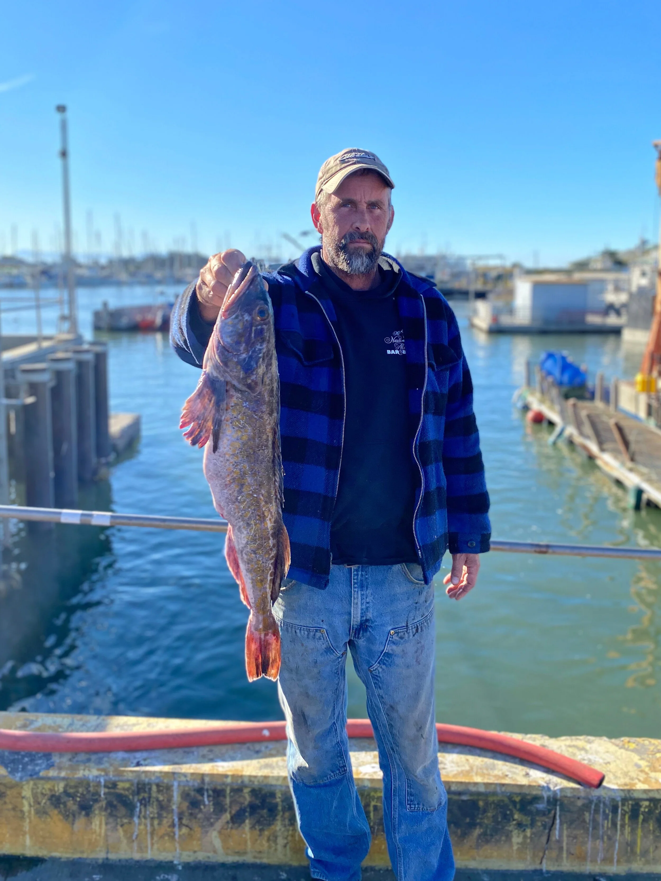 Captain Clint Beasley of the F/V Queen Corinne hold a fresh-caught lingcod in Moss Landing. Photo courtesy of Peter Adame/Lusamerica.